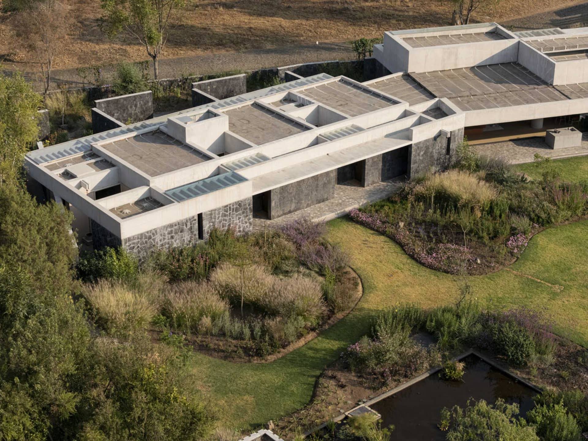 A modern concrete residential building with a green lawn and garden.