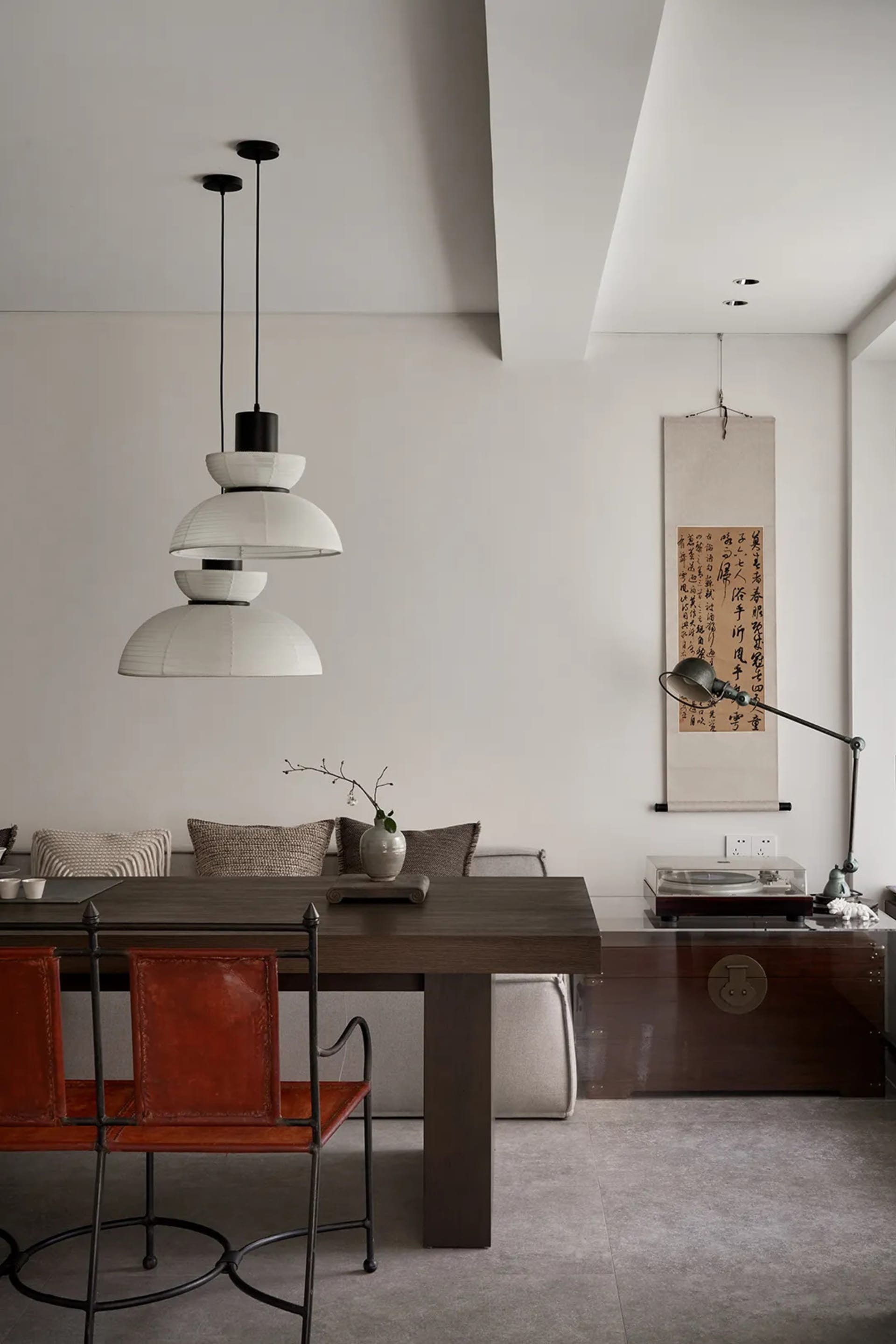 A modern interior design featuring a wooden dining table, leather chairs, and minimalist decor elements.