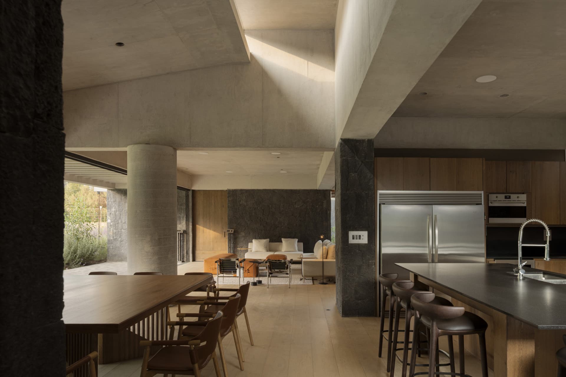 Contemporary residential interior featuring concrete walls and wooden dining area.