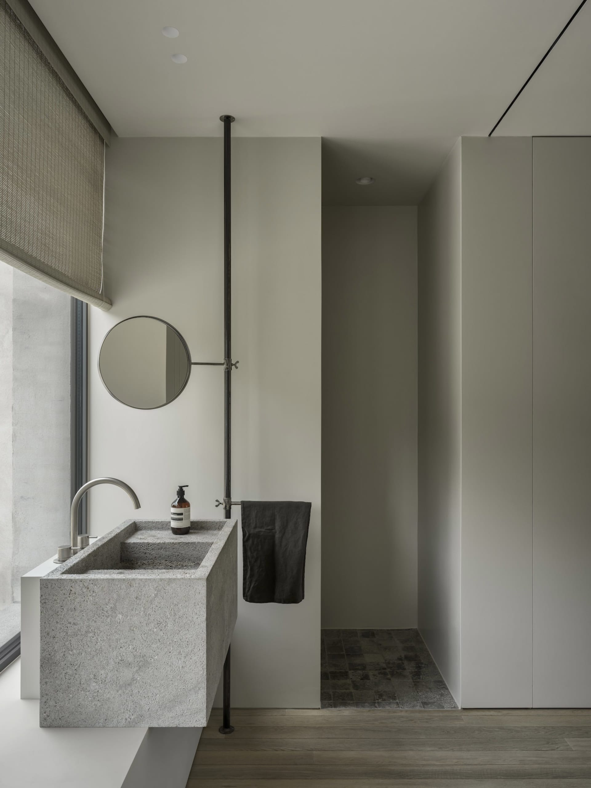 Modern minimalist bathroom featuring a concrete sink and metal fixtures.