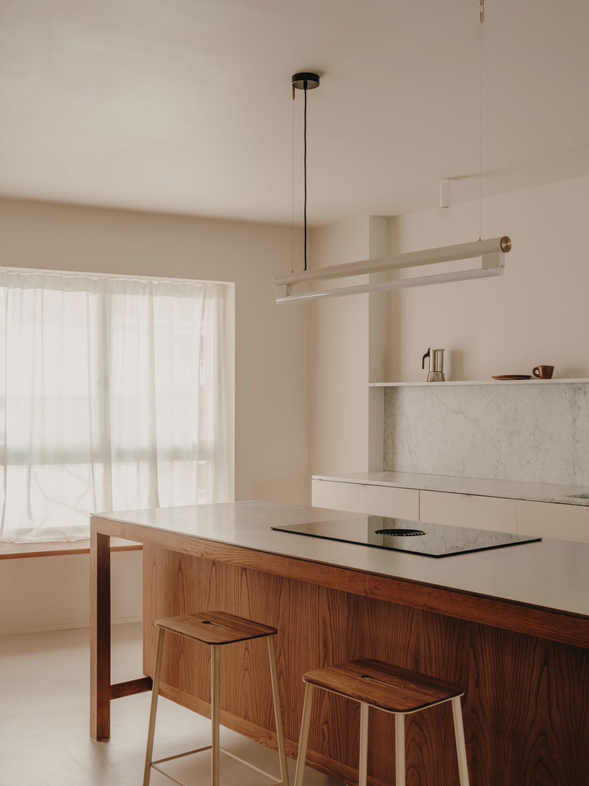 A minimalist residential kitchen with a wooden island and marble countertop.