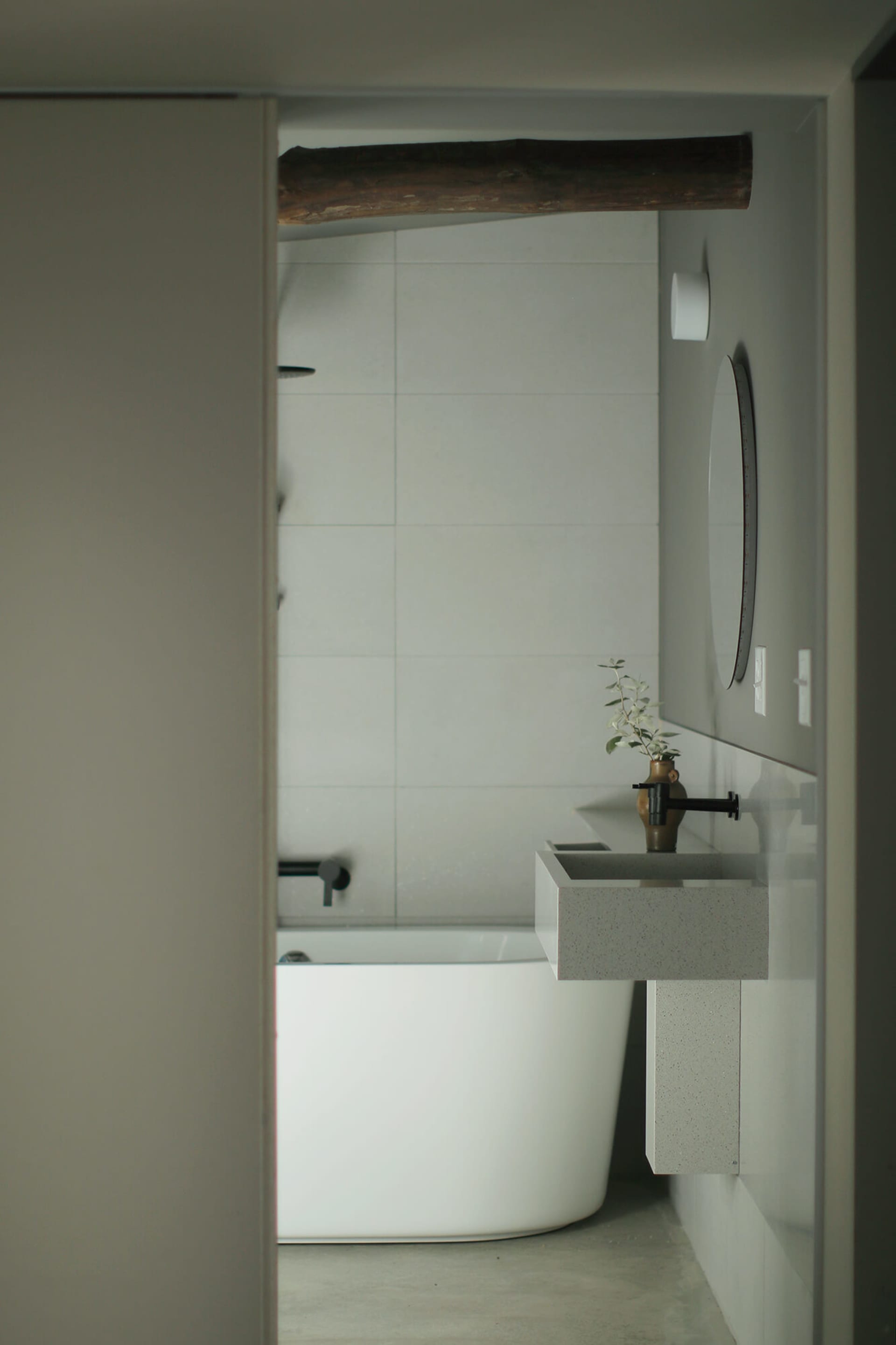 Minimalist bathroom with concrete walls and a freestanding white bathtub.
