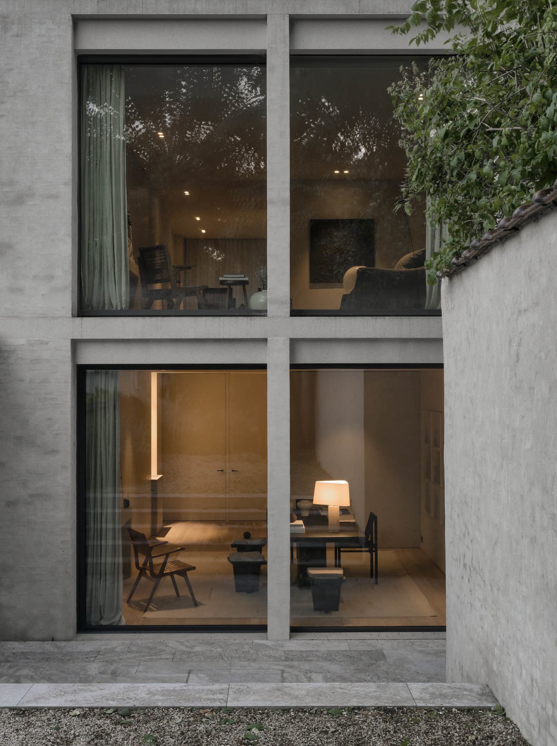A modern interior space featuring concrete walls, glass windows, and wooden furniture.