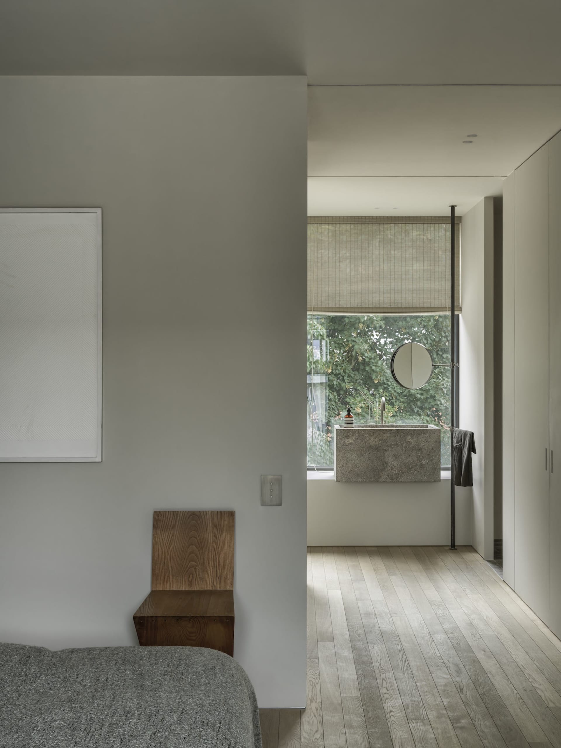 A modern minimalist bathroom featuring a stone sink and mirror.