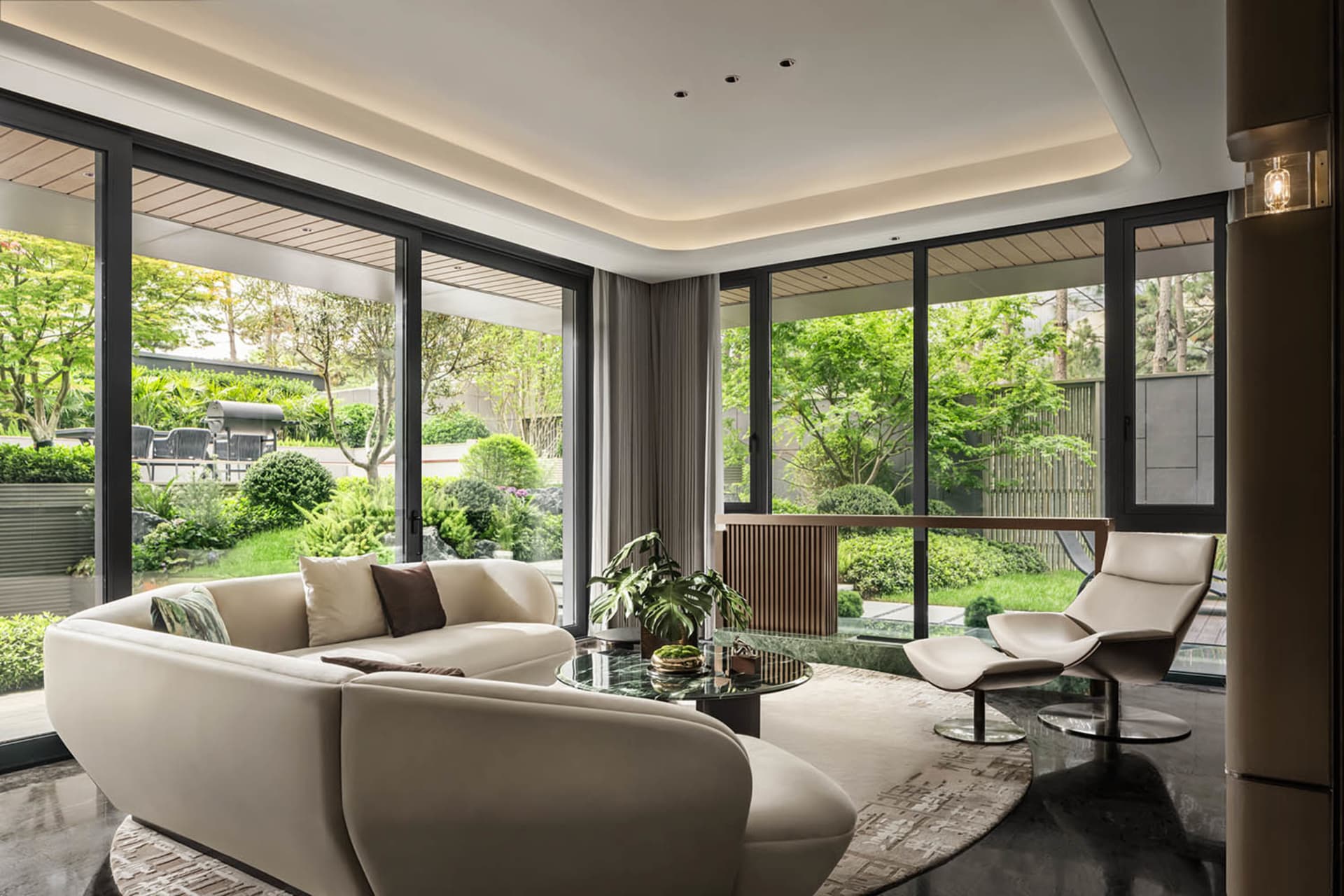 A modern contemporary living room featuring leather sofas, glass coffee table, and stone flooring.