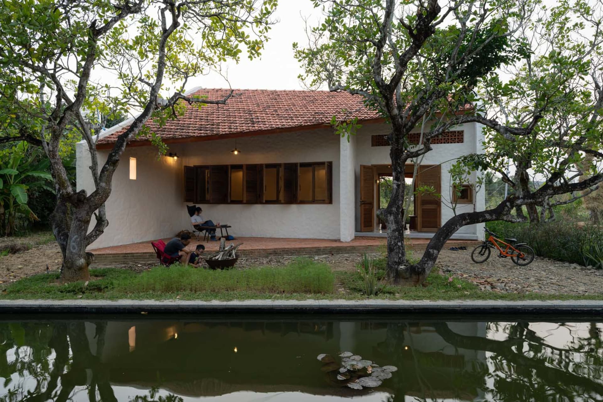 A modern residential cottage with a pool surrounded by greenery and a bicycle parked nearby.