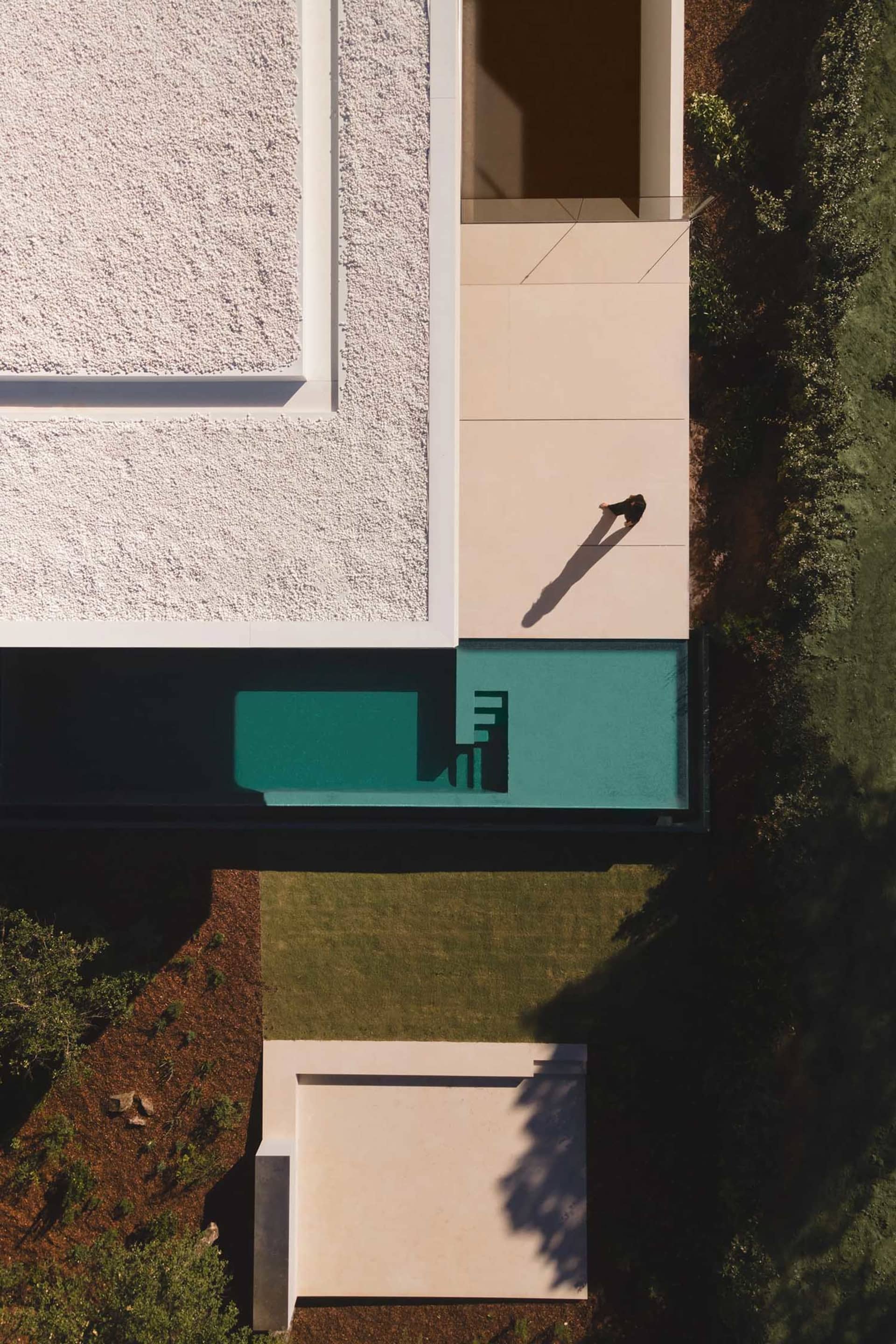 A modern pool house exterior featuring clean lines, white walls, and a minimalist outdoor space.