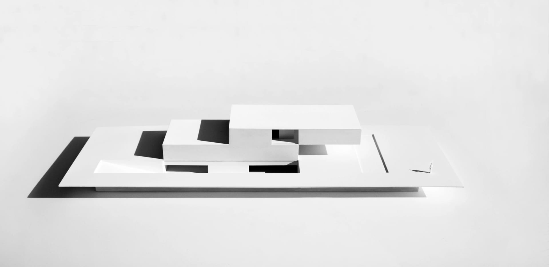 A minimalist architectural model made of white material, featuring clean lines and geometric shapes.