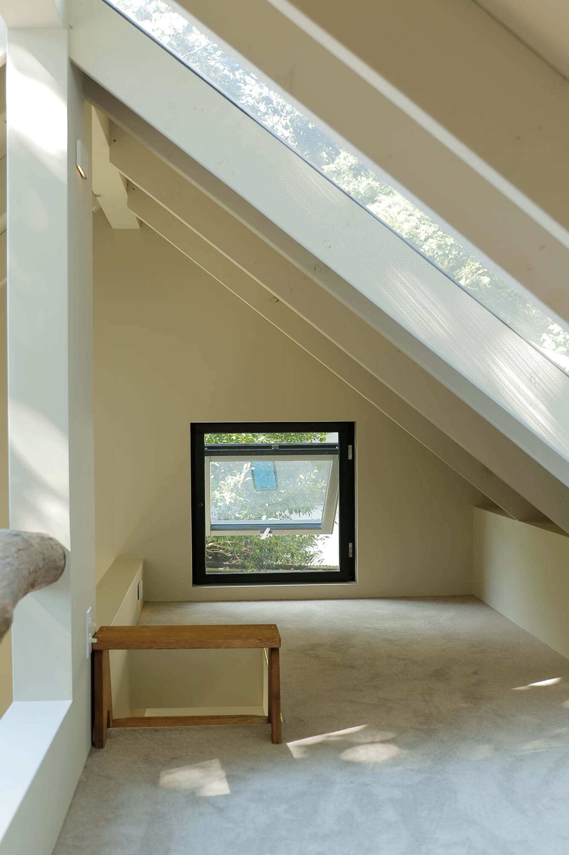 A minimalist bedroom featuring wooden furniture, carpet flooring, and large windows with glass.