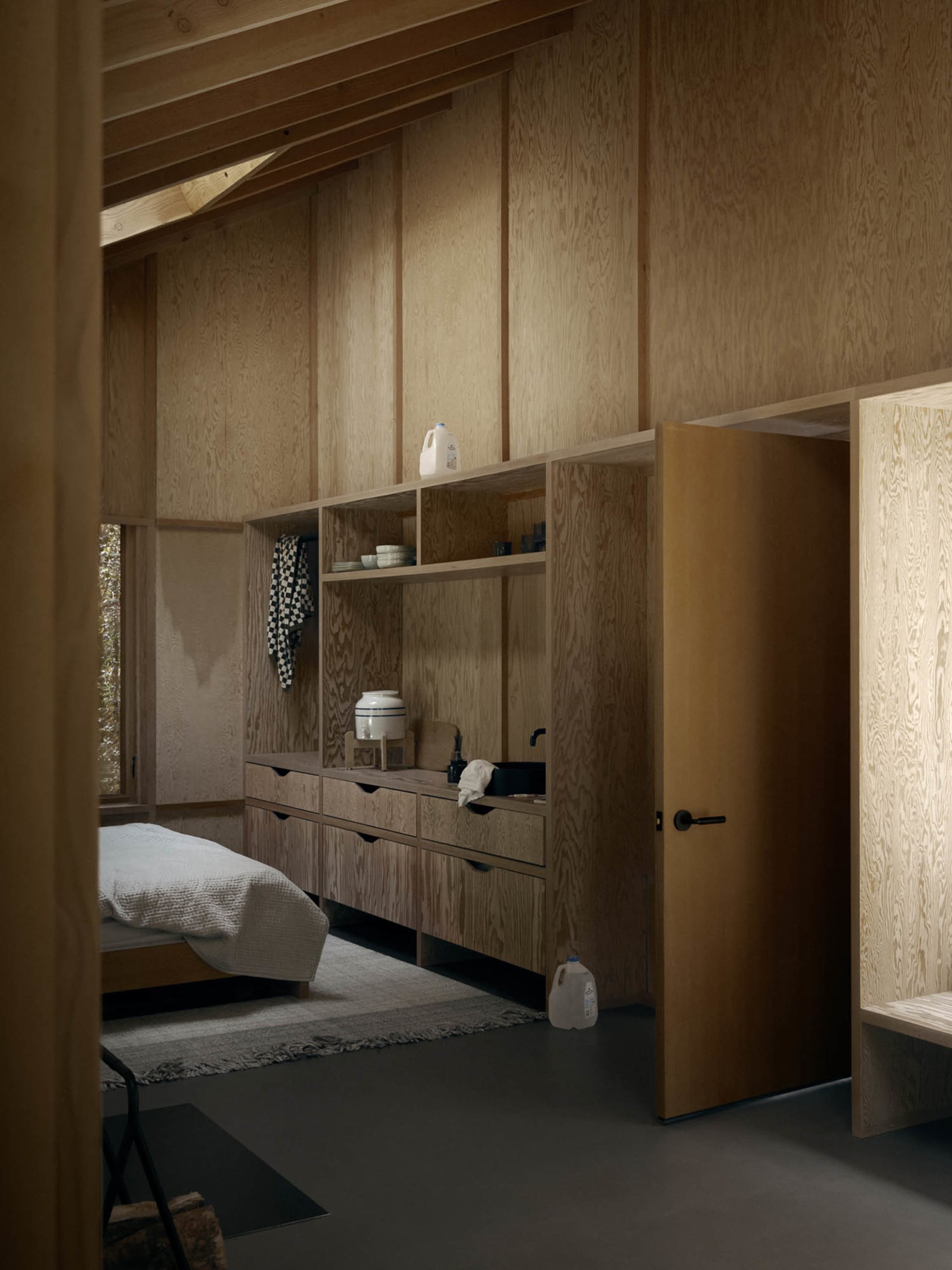 A minimalist residential kitchen featuring wooden cabinets and shelves.