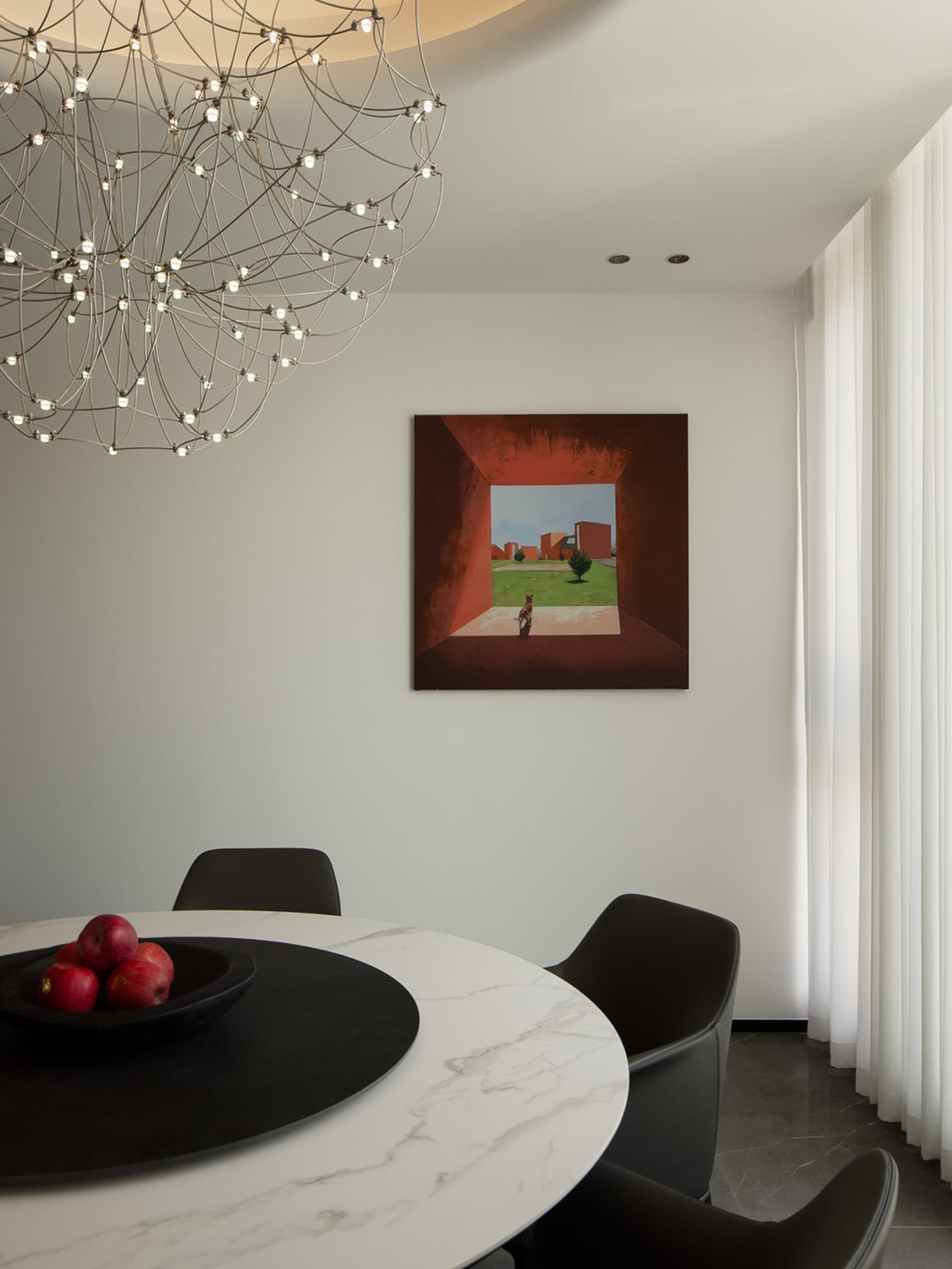 Modern dining room featuring a white marble table with black marble accents and a black chandelier hanging from the ceiling.