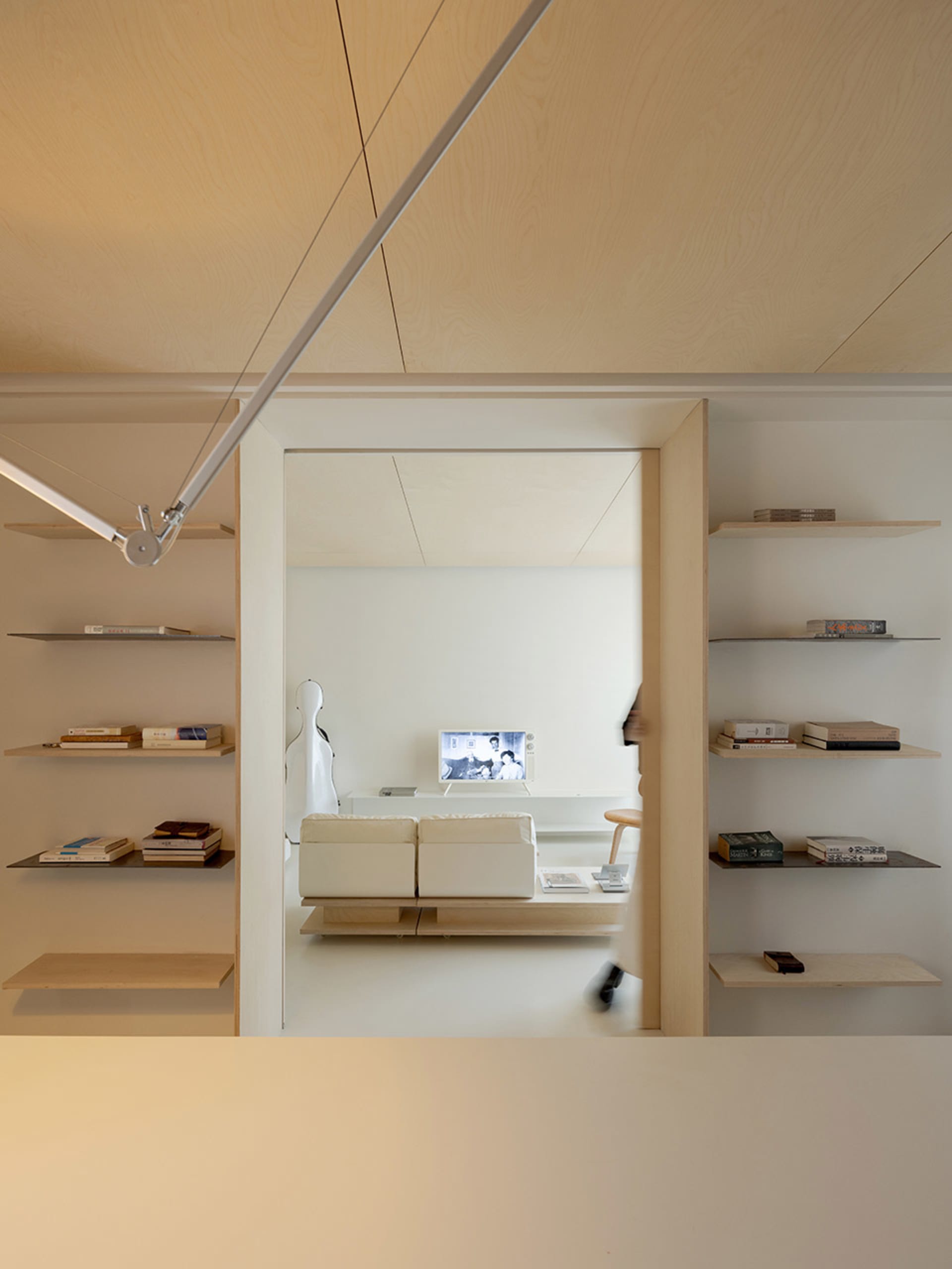 A modern living room with white walls, wooden shelves, and a white sofa.
