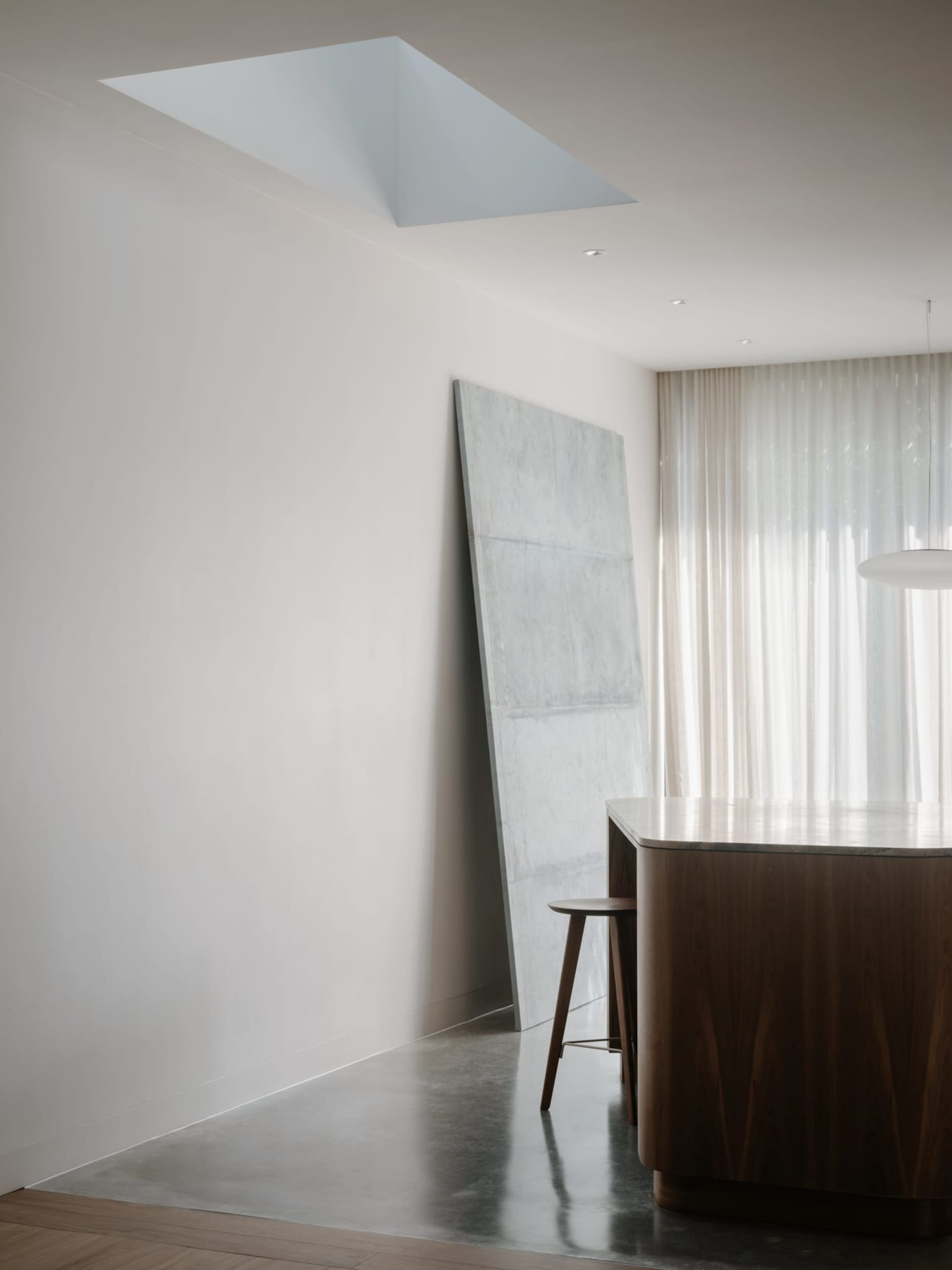 A minimalist kitchen featuring modern design elements with marble and concrete finishes.