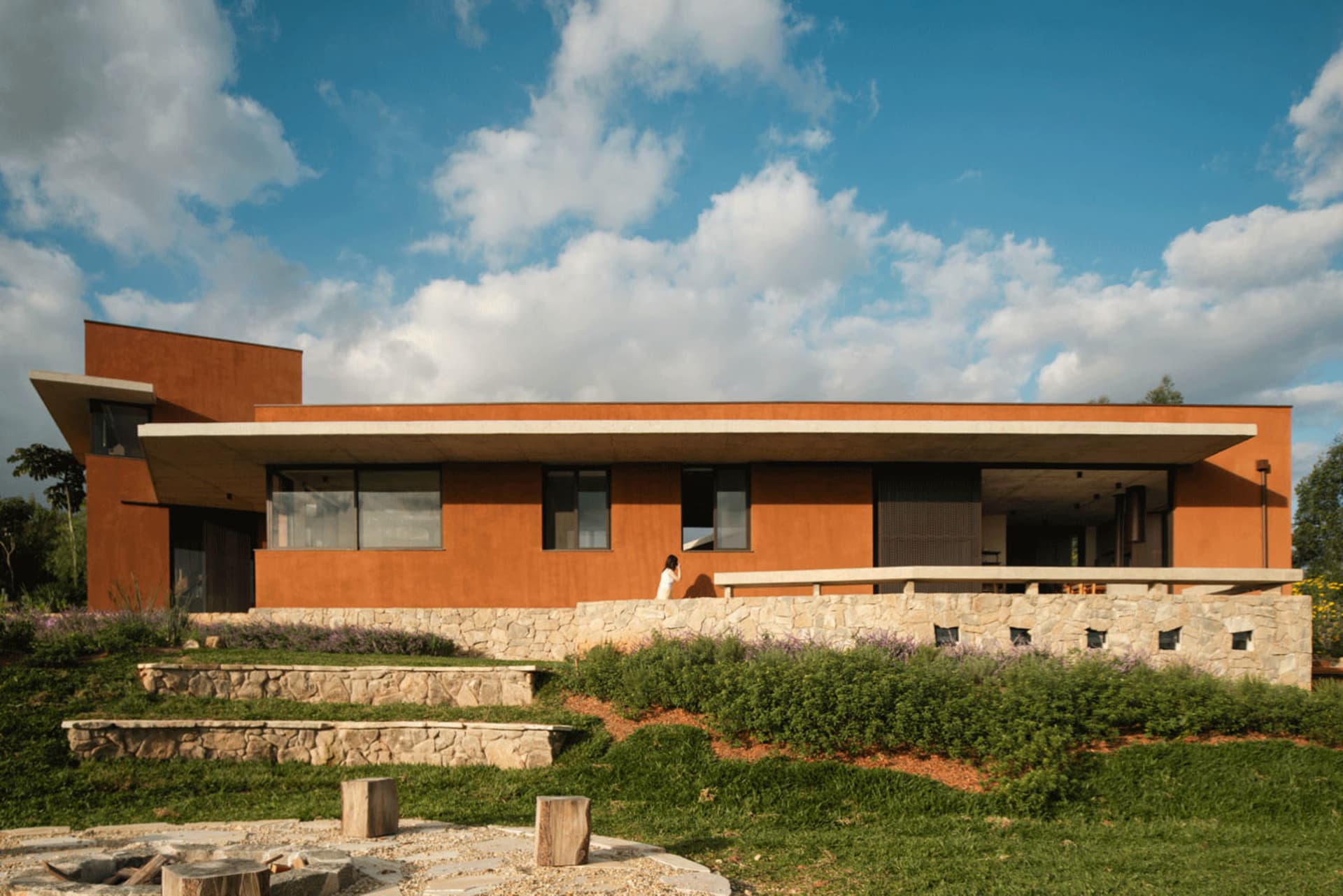 A modern house with a clay exterior, featuring a wide overhang and large windows.