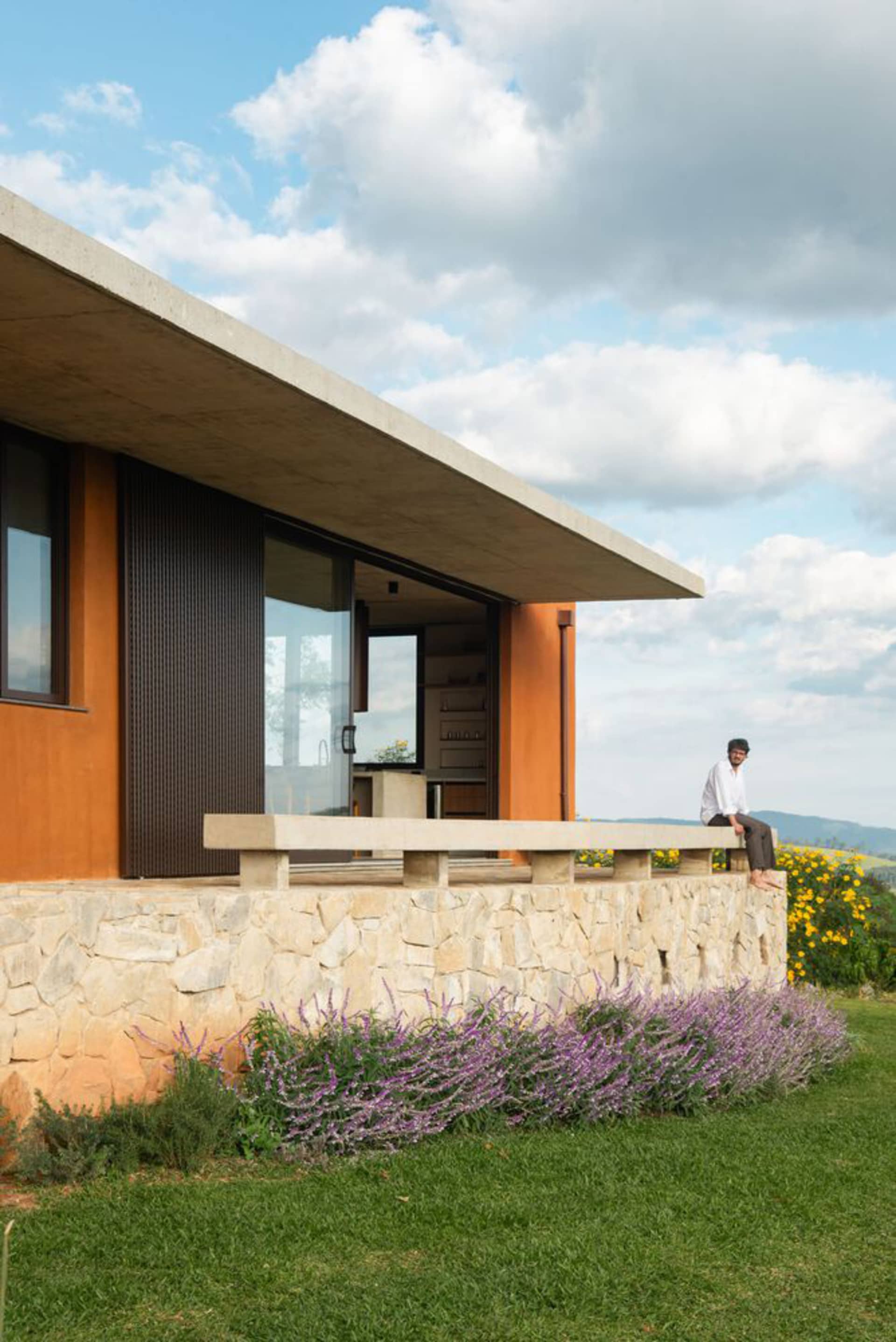 A modern residential exterior featuring stucco, stone, and concrete materials.