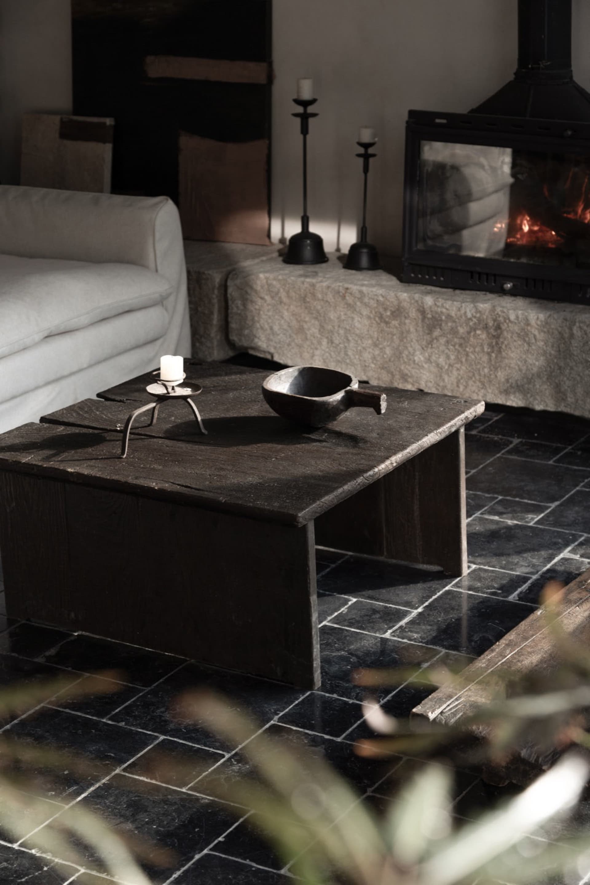 A rustic living room featuring a wooden table with a stone fireplace in the background.