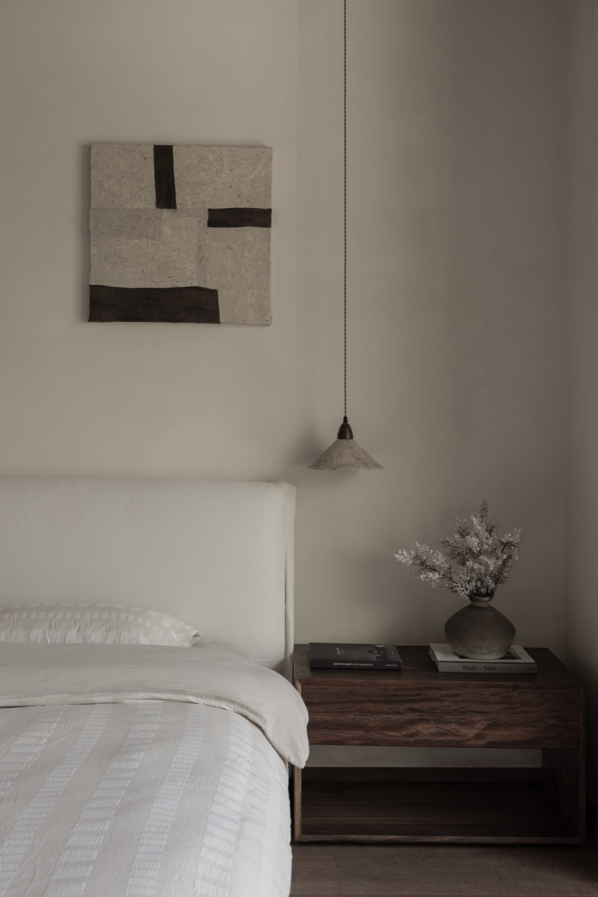 Minimalist bedroom with white bedding and a wooden nightstand.