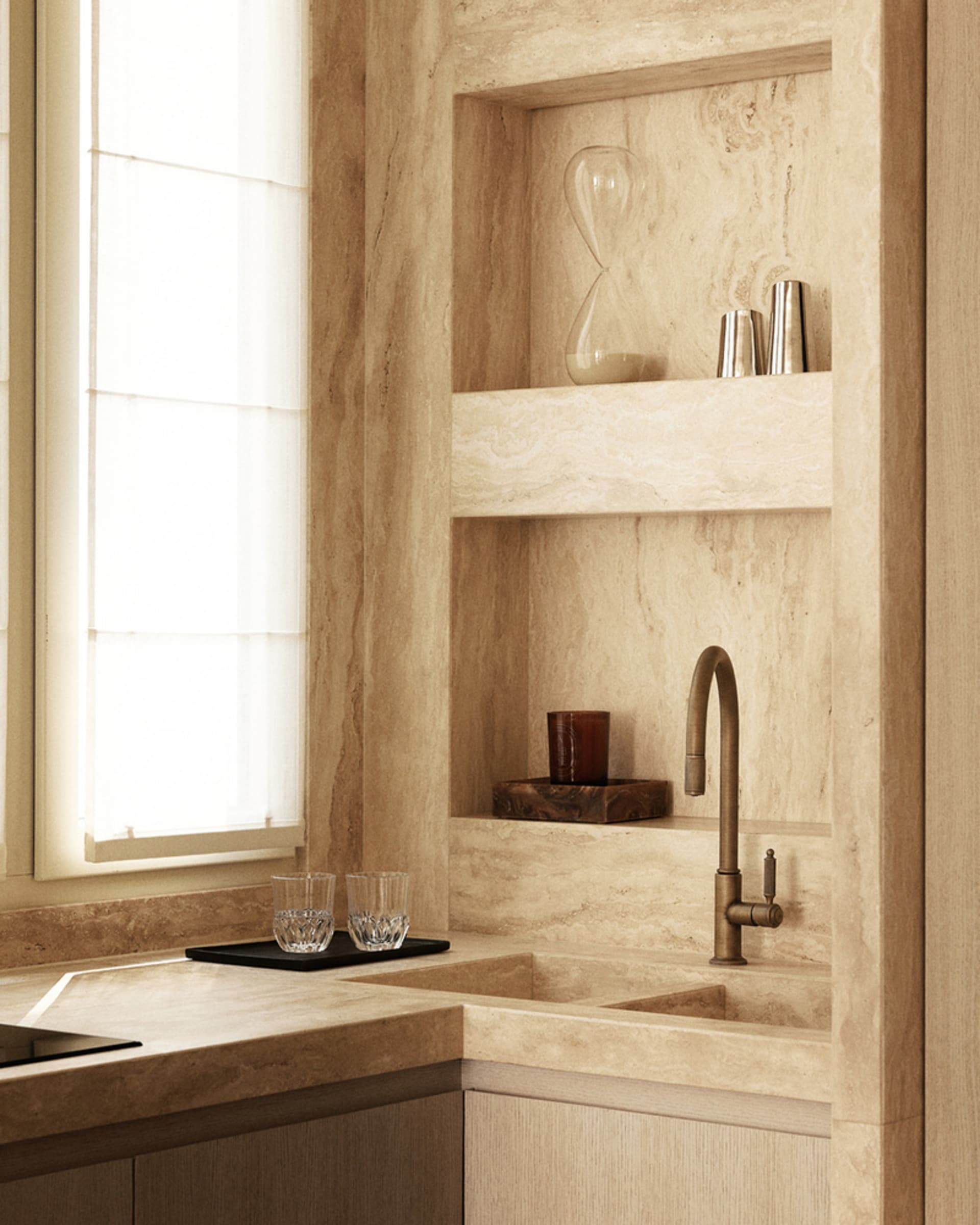 A minimalist kitchen featuring a marble countertop and sink with a decorative hourglass on a shelf.
