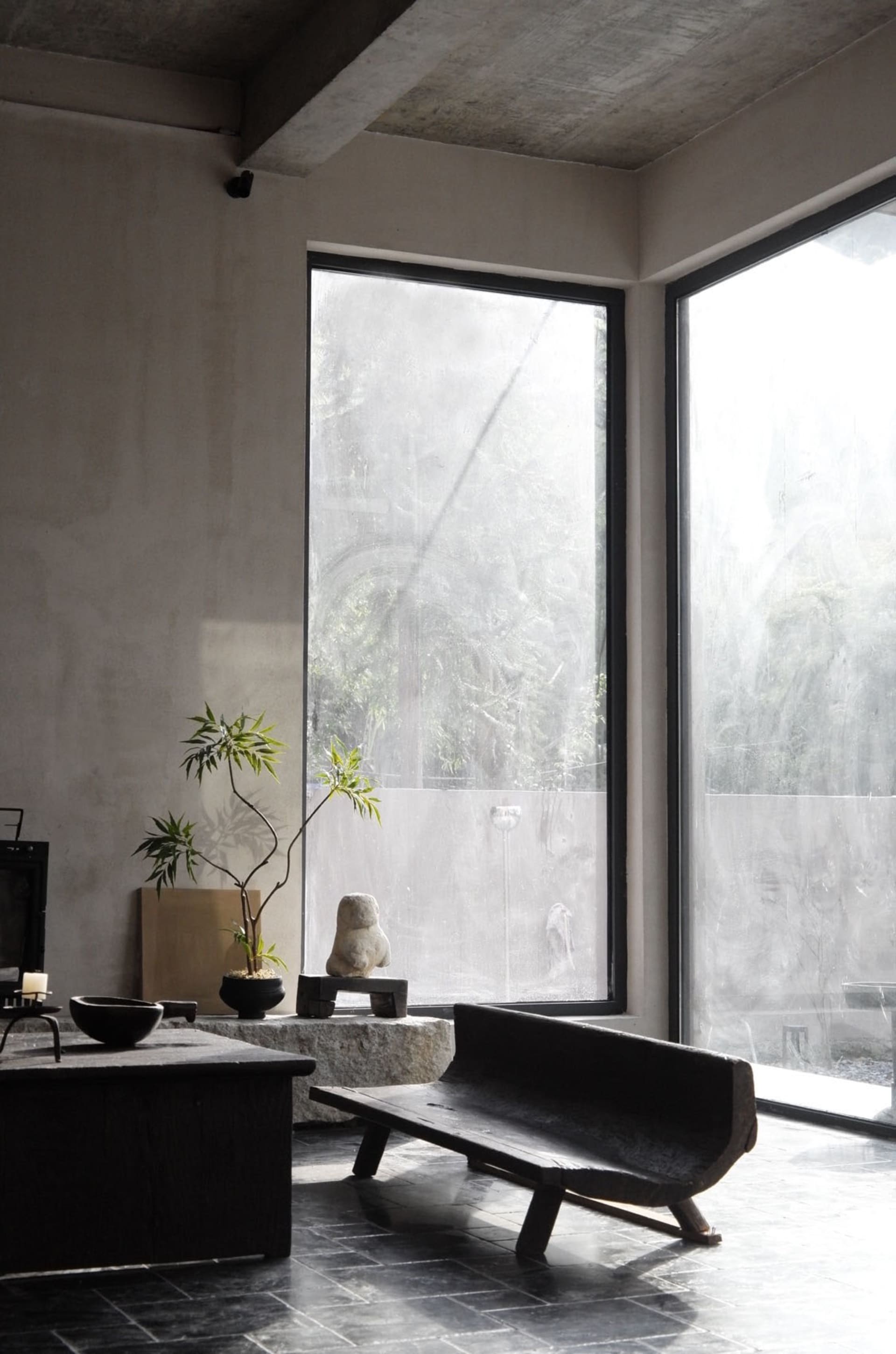 Minimalist living room with concrete elements and large windows.
