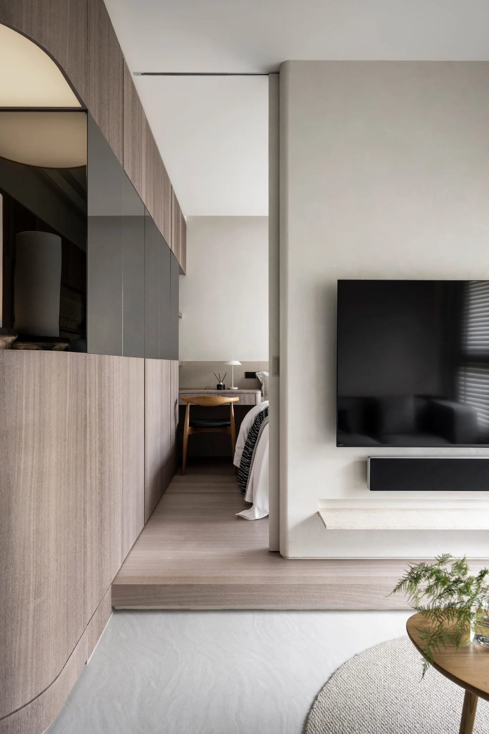Modern minimalist living room featuring a flat-screen TV mounted on a wall, surrounded by sleek, contemporary furnishings and