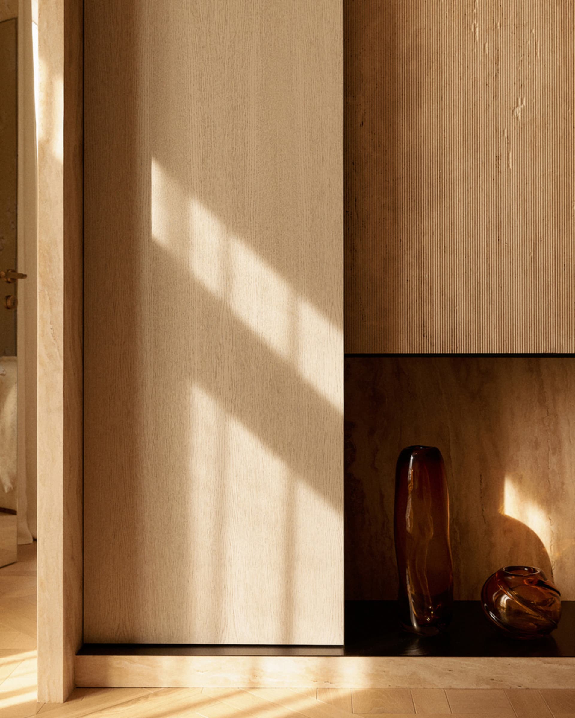 Minimalist living space featuring natural wood paneled walls and floor, with light streaming in through the window.