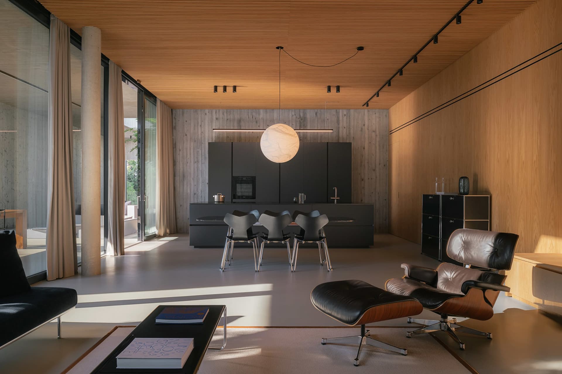 A modern living room featuring black metal kitchen cabinets and wood-textured walls and ceiling.