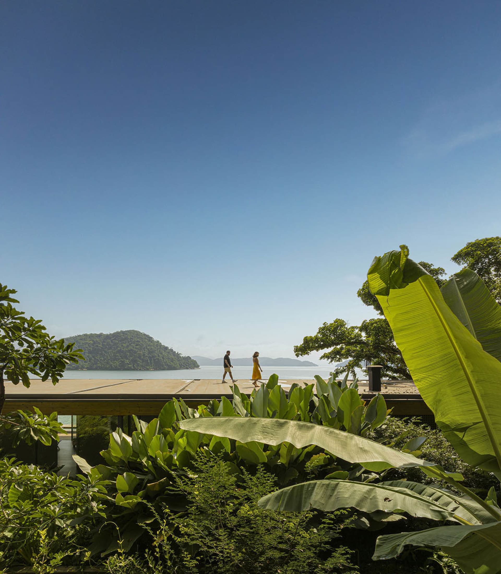 一棟現代度假別墅,擁有玻璃牆、木質露台,以及全景海景。