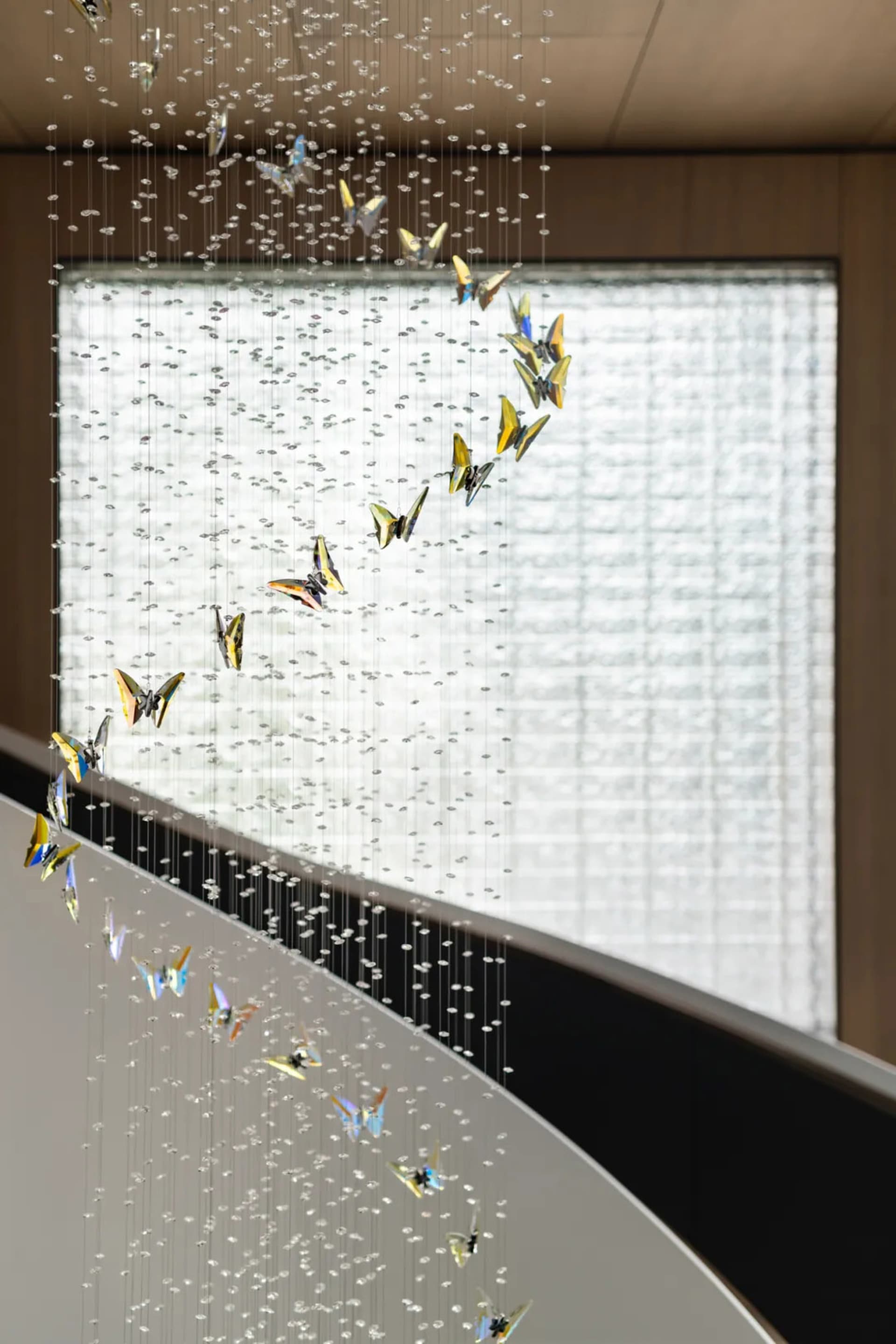 A contemporary glass chandelier sculpture hanging from the ceiling in an elegant interior space.