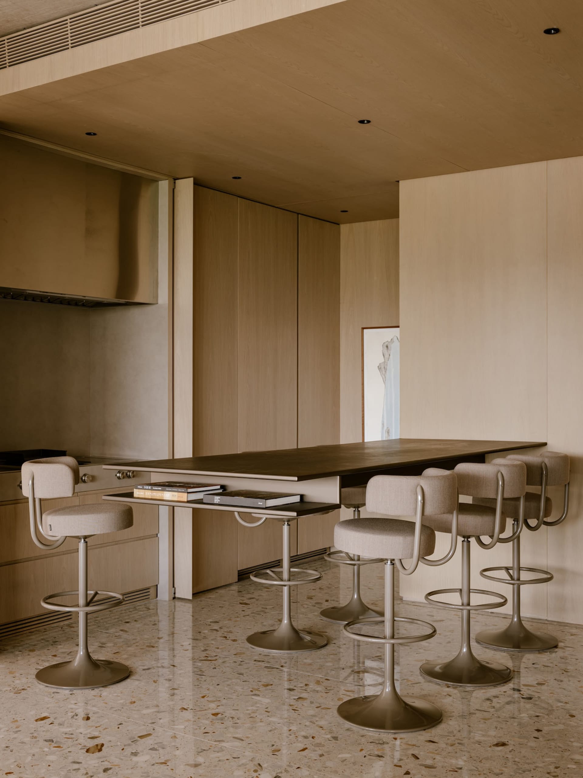 Modern kitchen with concrete countertop, featuring minimalist design and high stools for seating.