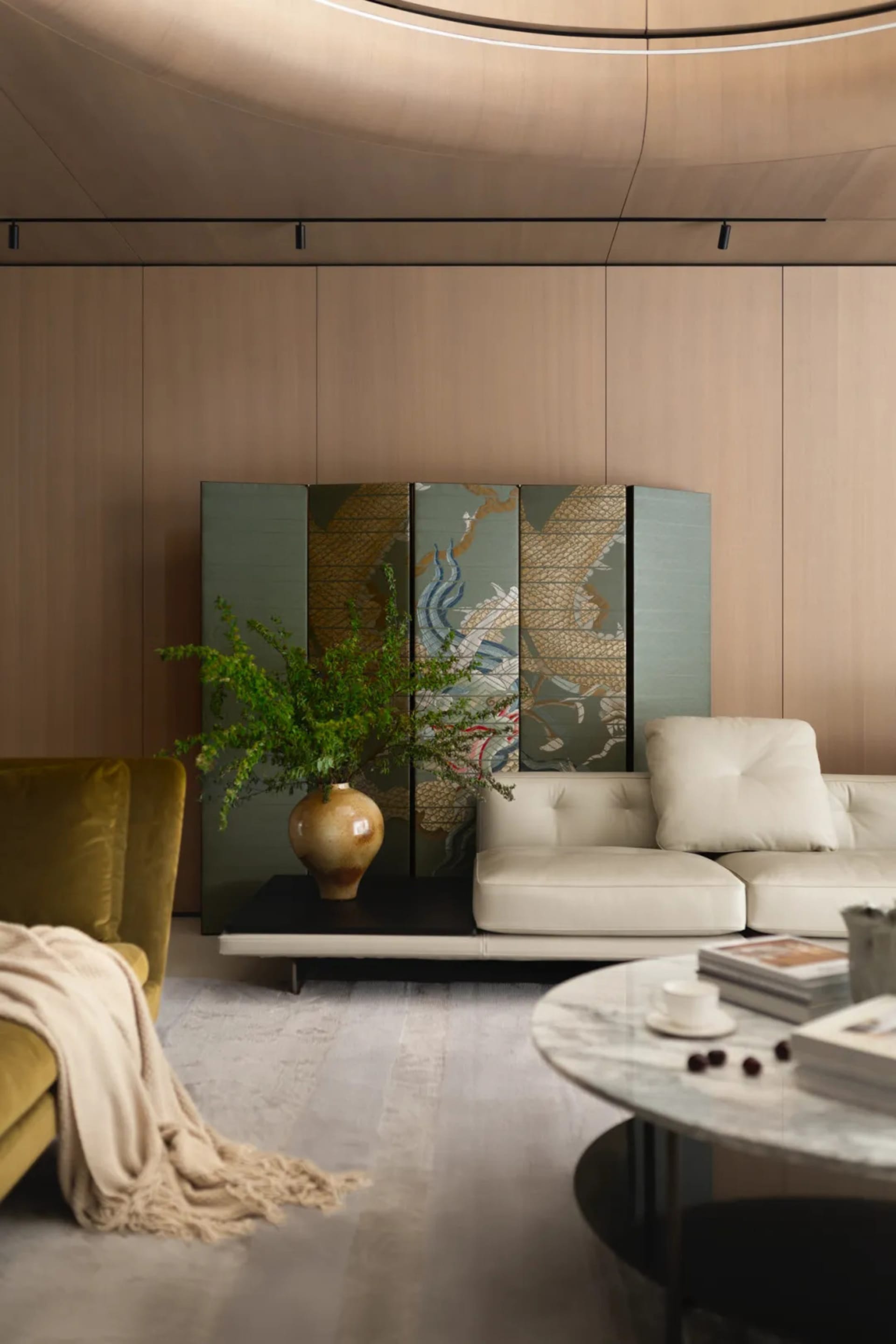 A modern living room featuring wood-paneled walls, a white leather sofa, and a marble coffee table with a vase of green plant