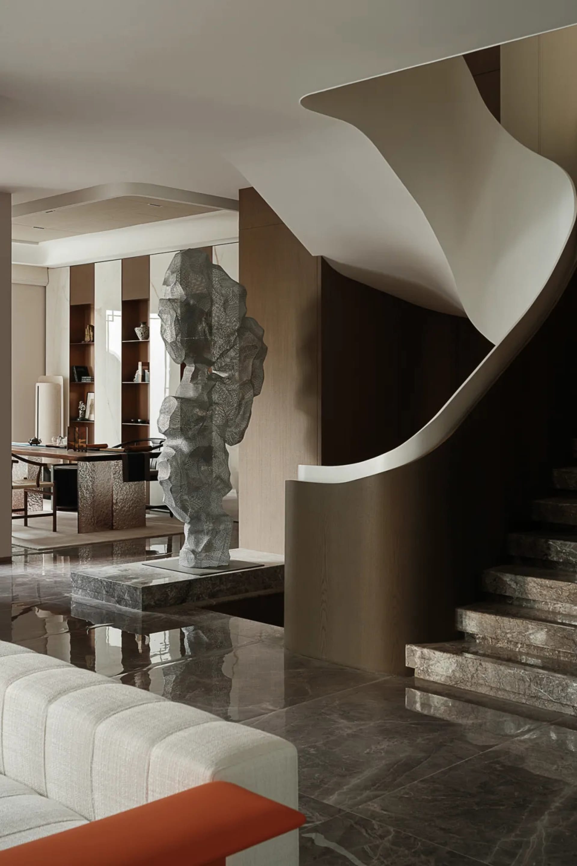 Modern living room with curved staircase and marble flooring.
