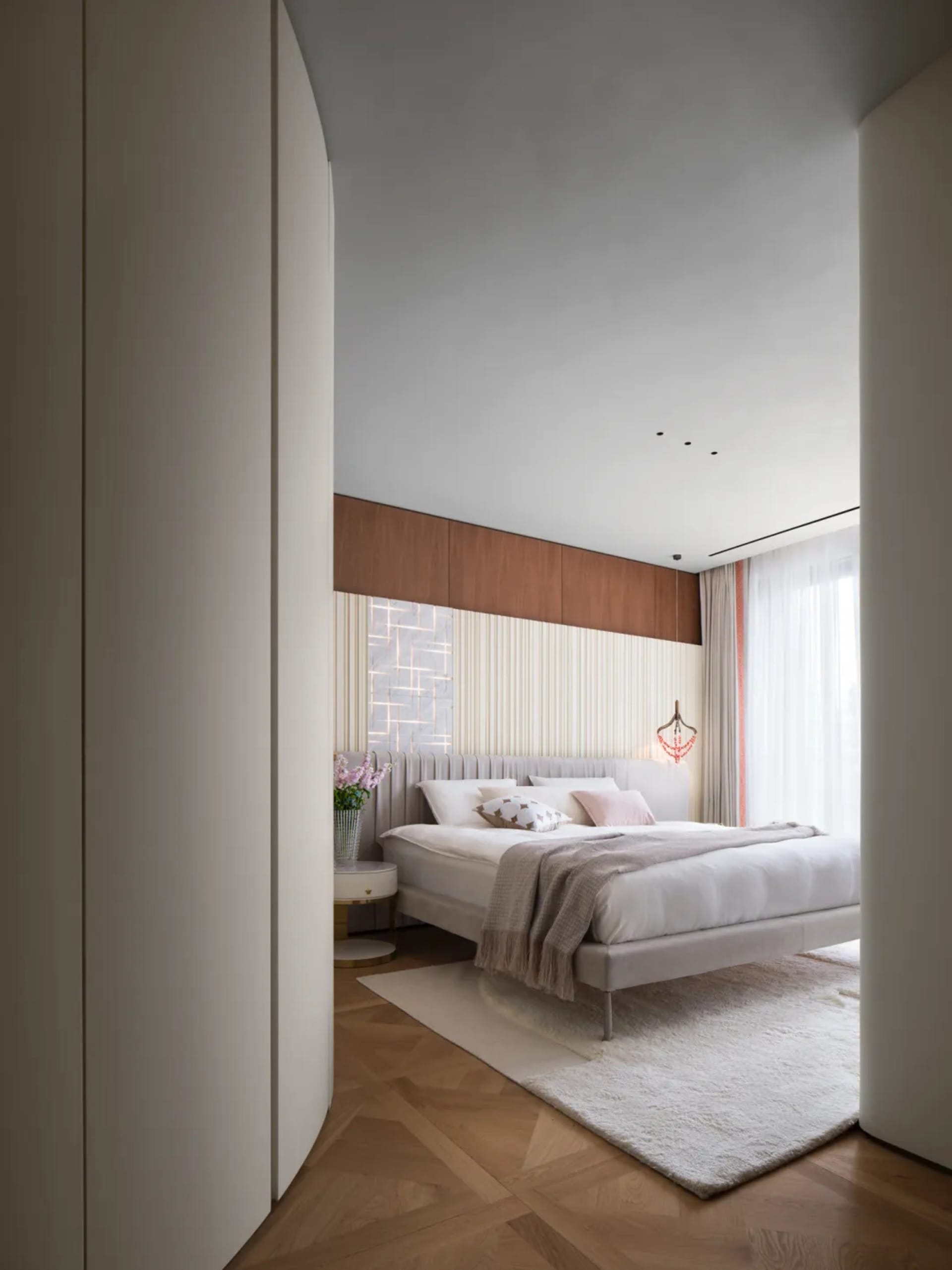 Modern bedroom featuring white furniture, wood floors, and a minimalist design.