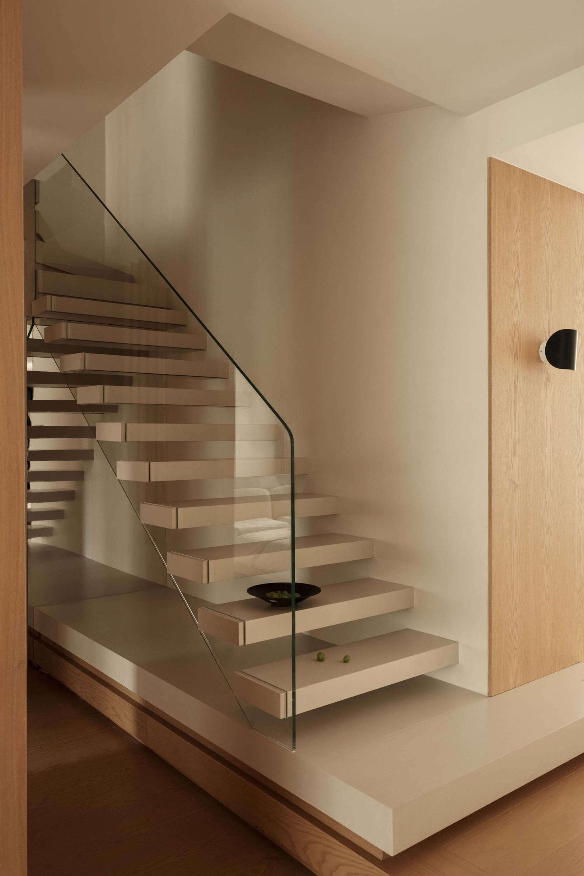 Modern, floating staircase made of wood with glass railings, minimalistic design.