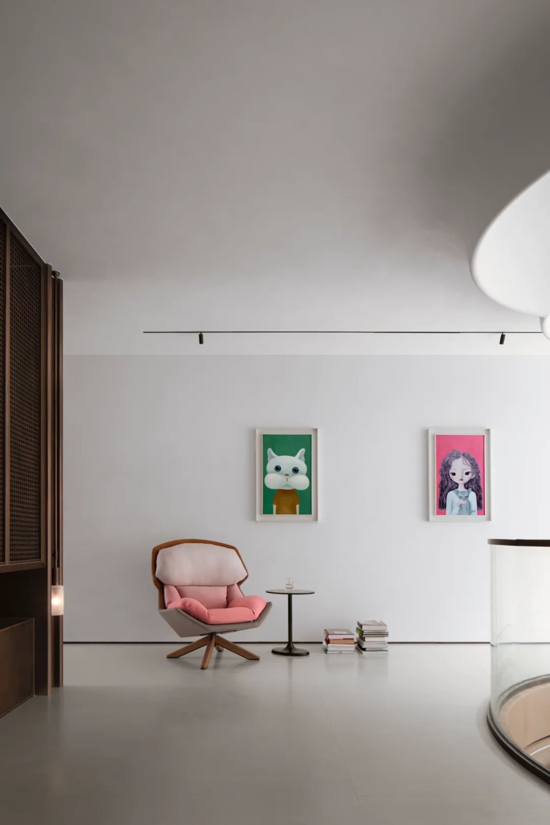 A minimalist modern living room with a concrete floor, wooden furniture, and a glass table.