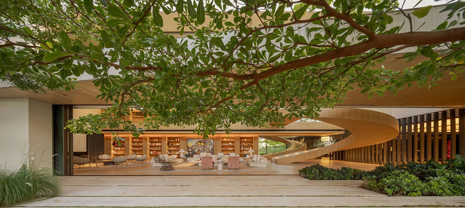 現代住宅客廳，木質地板與家具，搭配螺旋樓梯與綠意植栽。