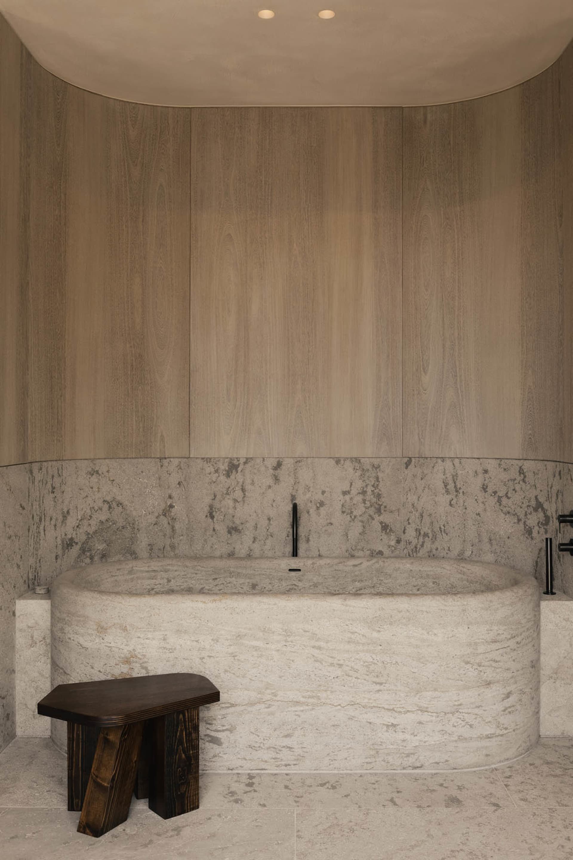 A minimalist bathroom featuring a marble bathtub and wooden accents.