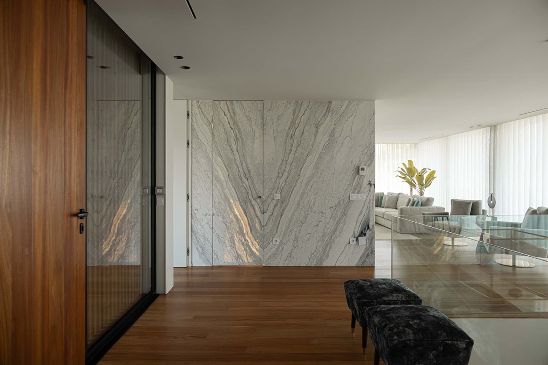 Modern living room showcasing marble, glass, and wood finishes.