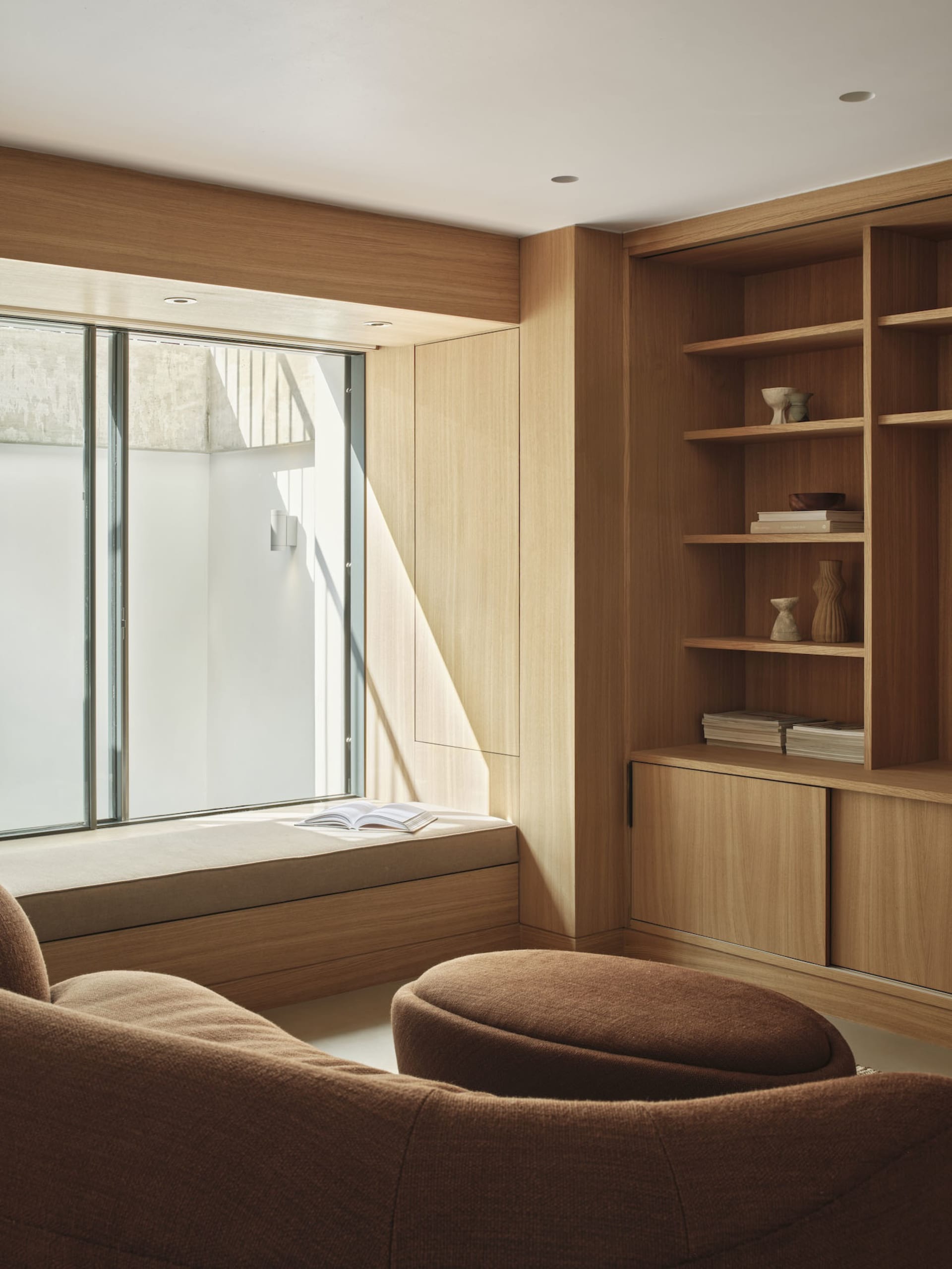 A minimalist living room with a window seat made of wood.