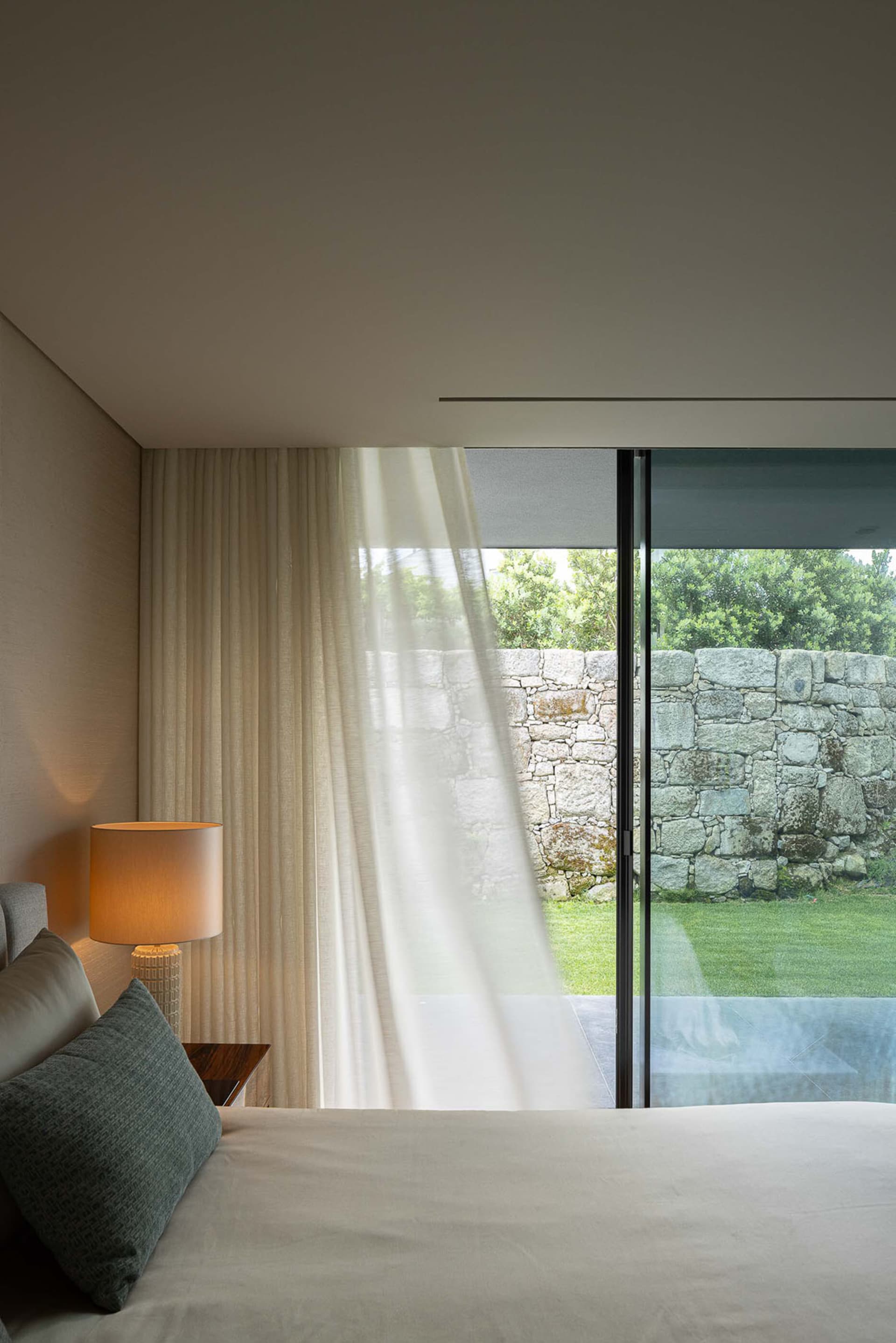 A modern bedroom featuring curtains and minimalist design.