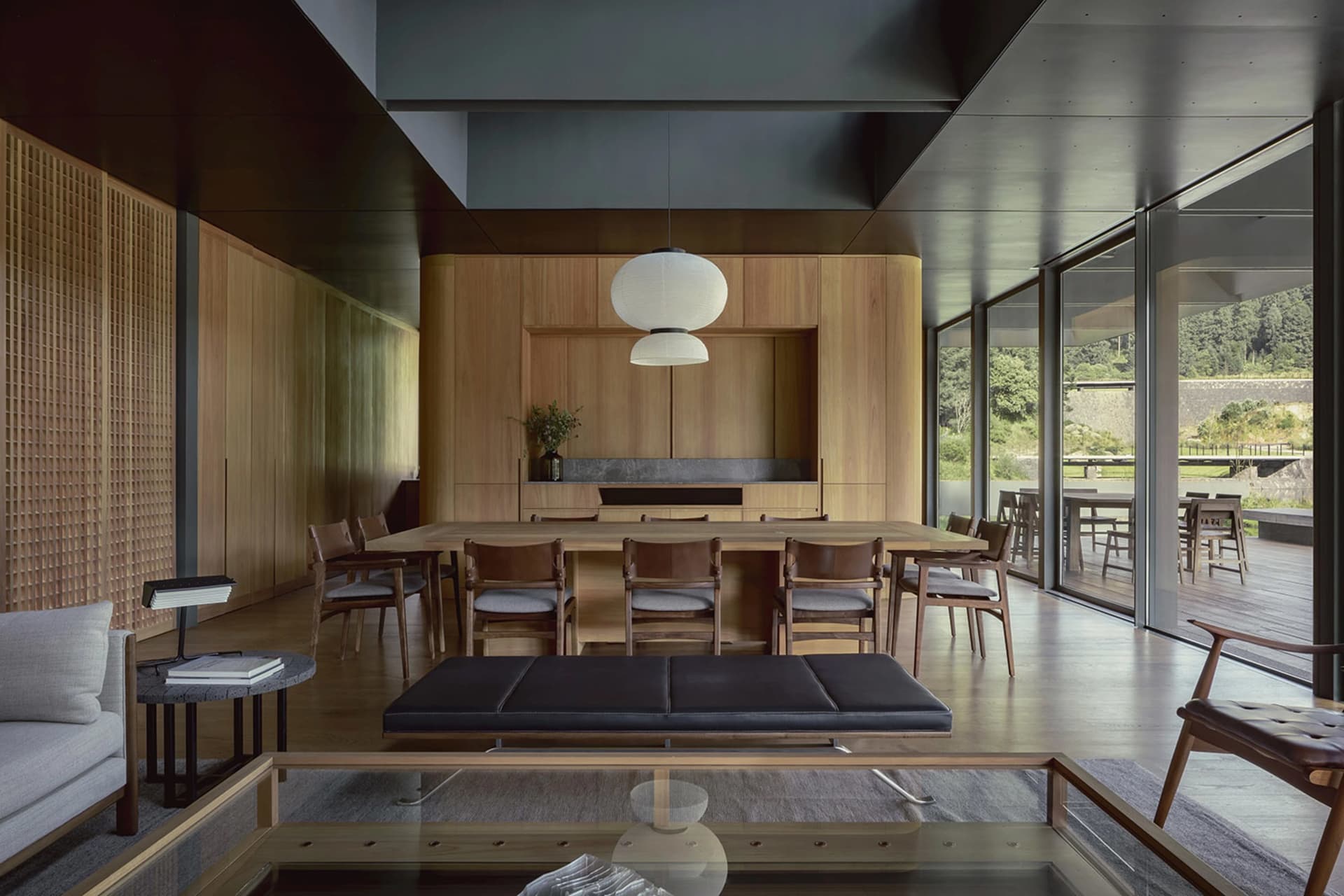 A modern dining room with wooden furniture and a large table surrounded by chairs, featuring a minimalist design with natural