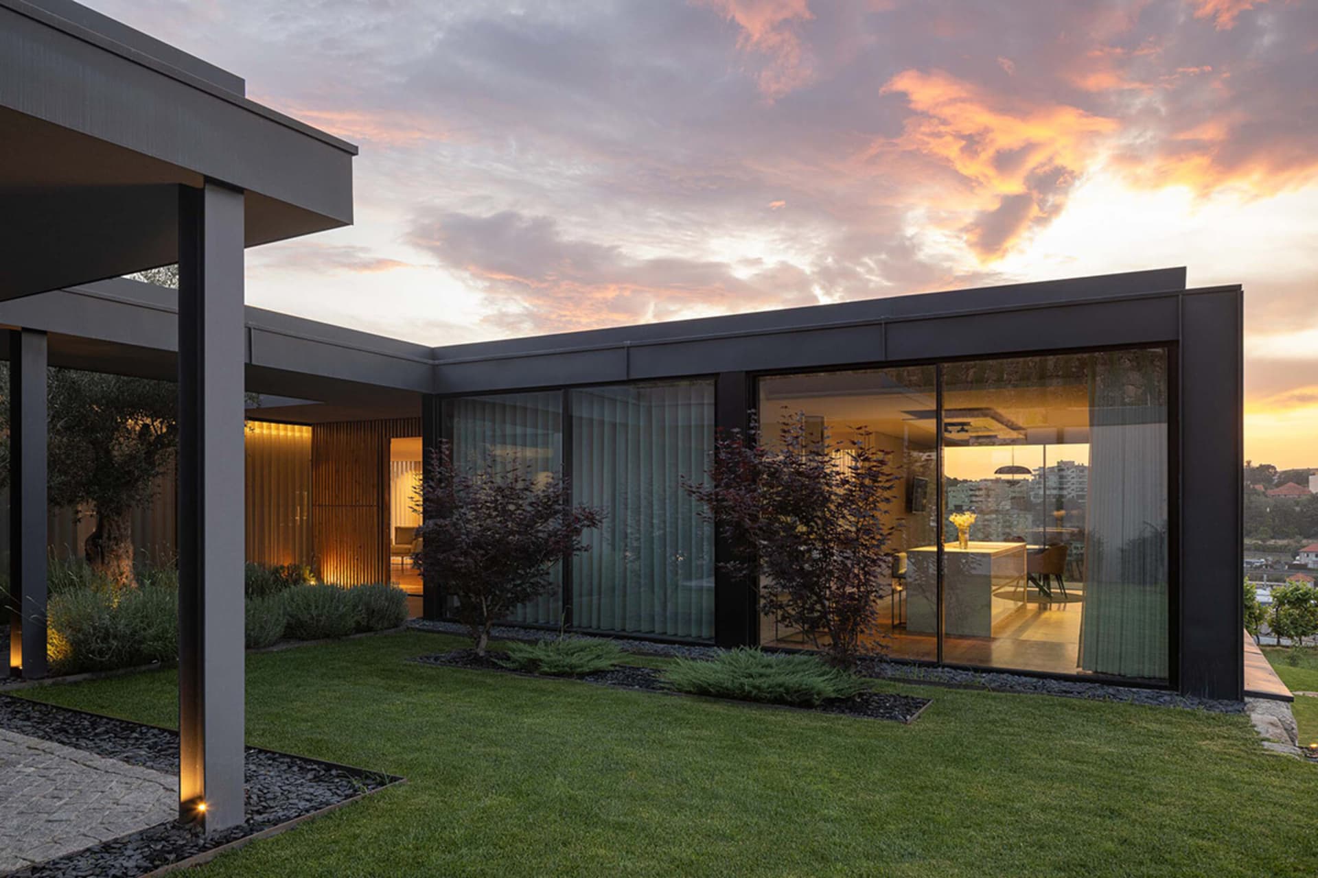Modern house exterior featuring large glass walls and a sleek, contemporary design.