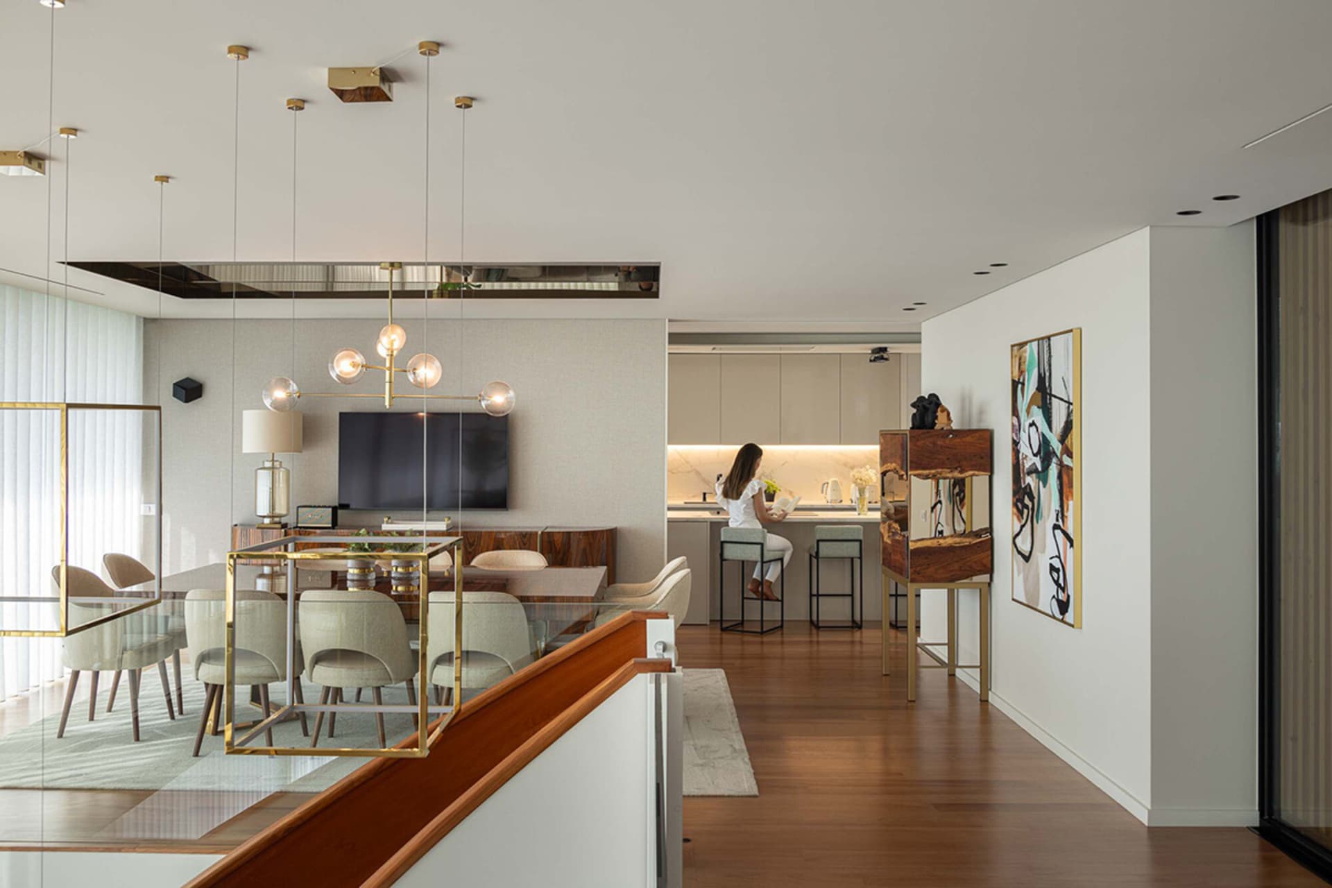 Modern living, dining, and kitchen area featuring wooden floors, glass tables, and metal furniture.