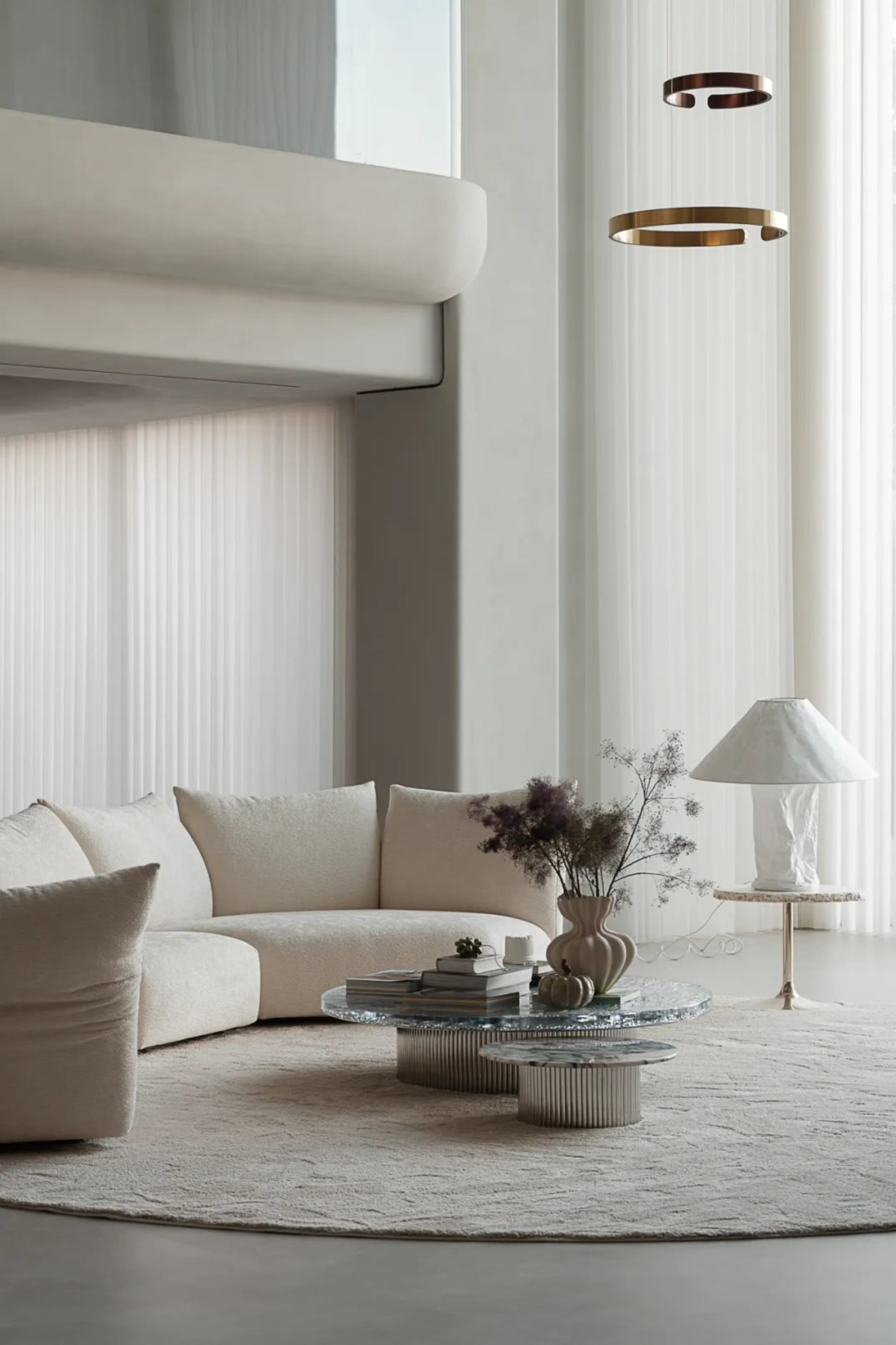 A modern living room featuring a curved sofa upholstered in neutral-toned leather, a round marble side table, and a hanging b