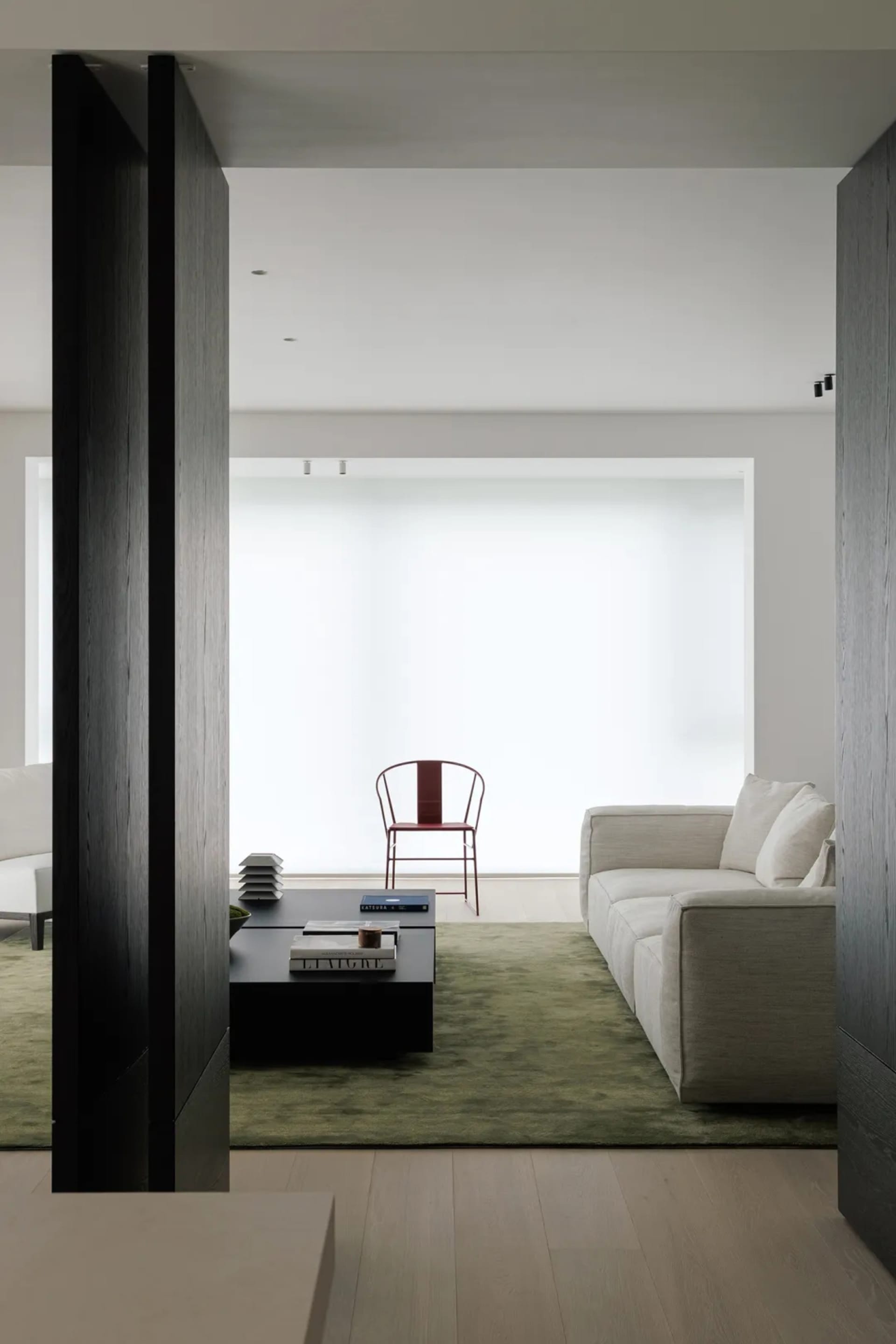 A modern living room featuring a white sofa on a green carpet with wooden panels and a minimalist design.