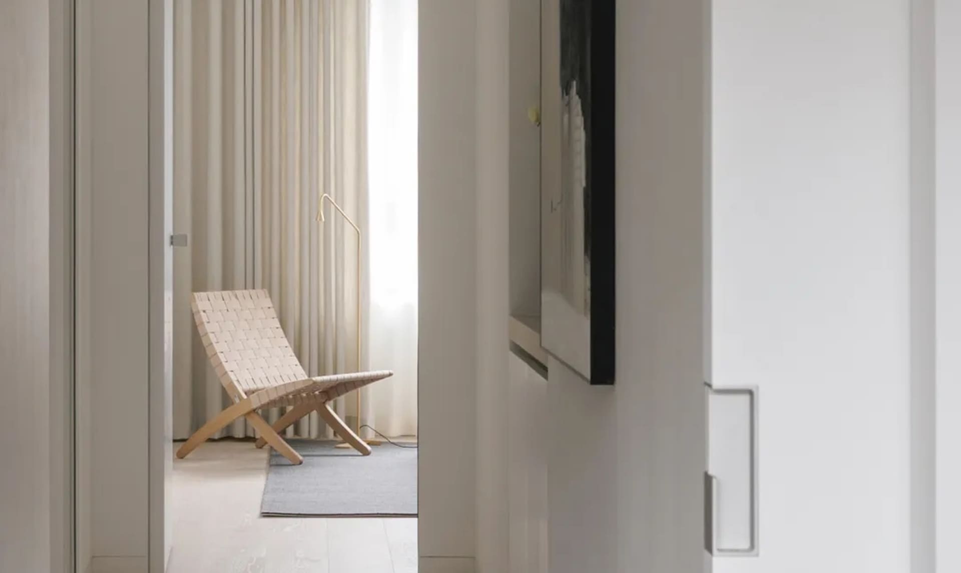 A minimalist living room featuring a modern woven chair against a textured fabric backdrop.
