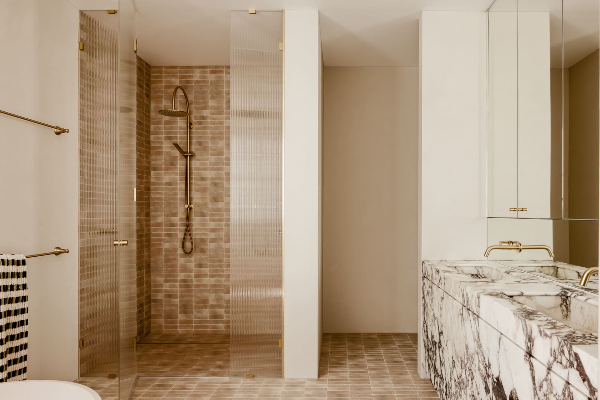 Modern bathroom featuring marble countertops and glass shower enclosure.