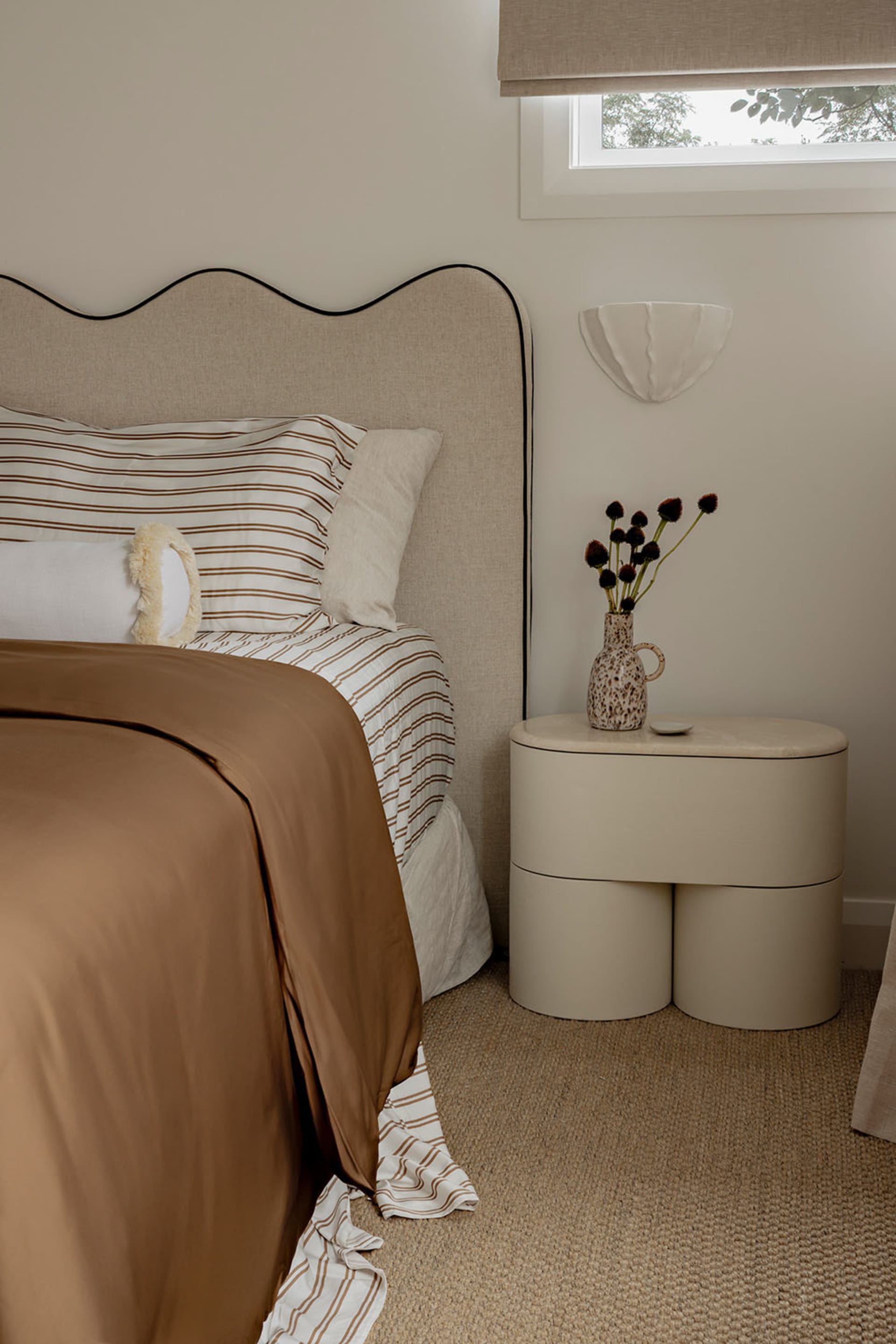 A modern minimalist bedroom with a comfortable bed and a unique nightstand.