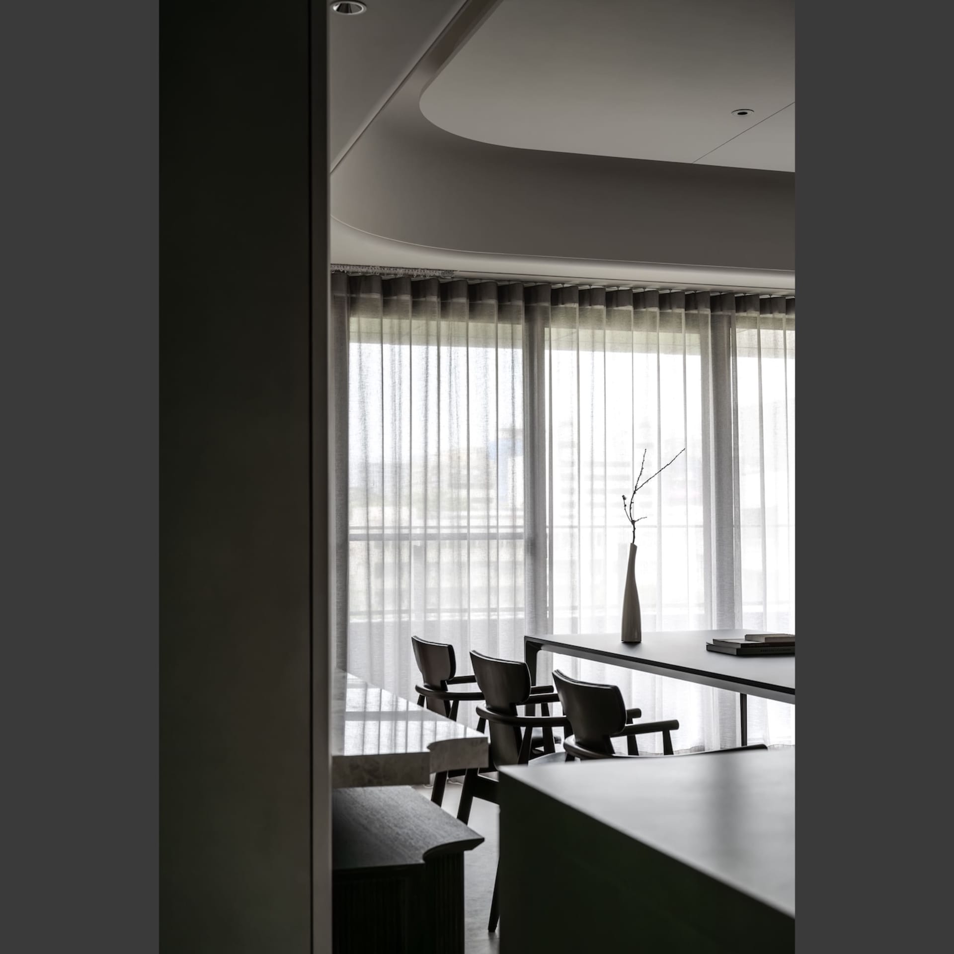 Modern dining room with neutral-tones furniture and transparent curtains.