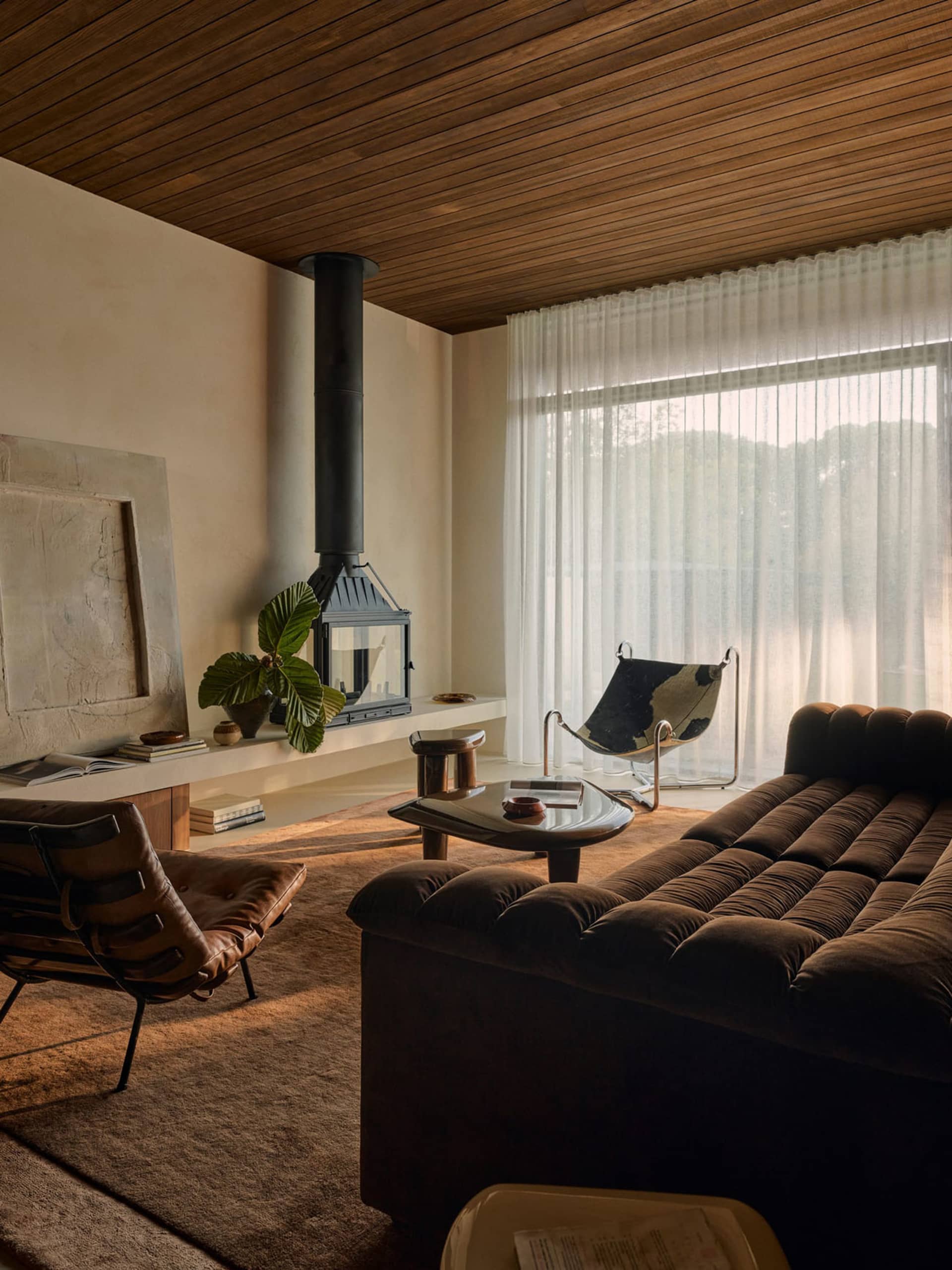 A modern living room featuring a cozy sofa adorned with plush cushions, set against a backdrop of warm wooden walls and ceili
