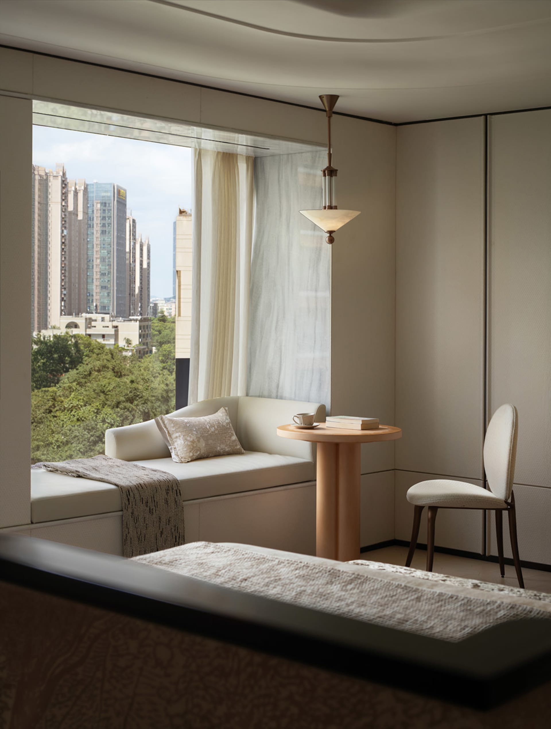 Modern living room featuring a cozy window sill with white upholstery, a small wooden table, and a comfortable seating area.